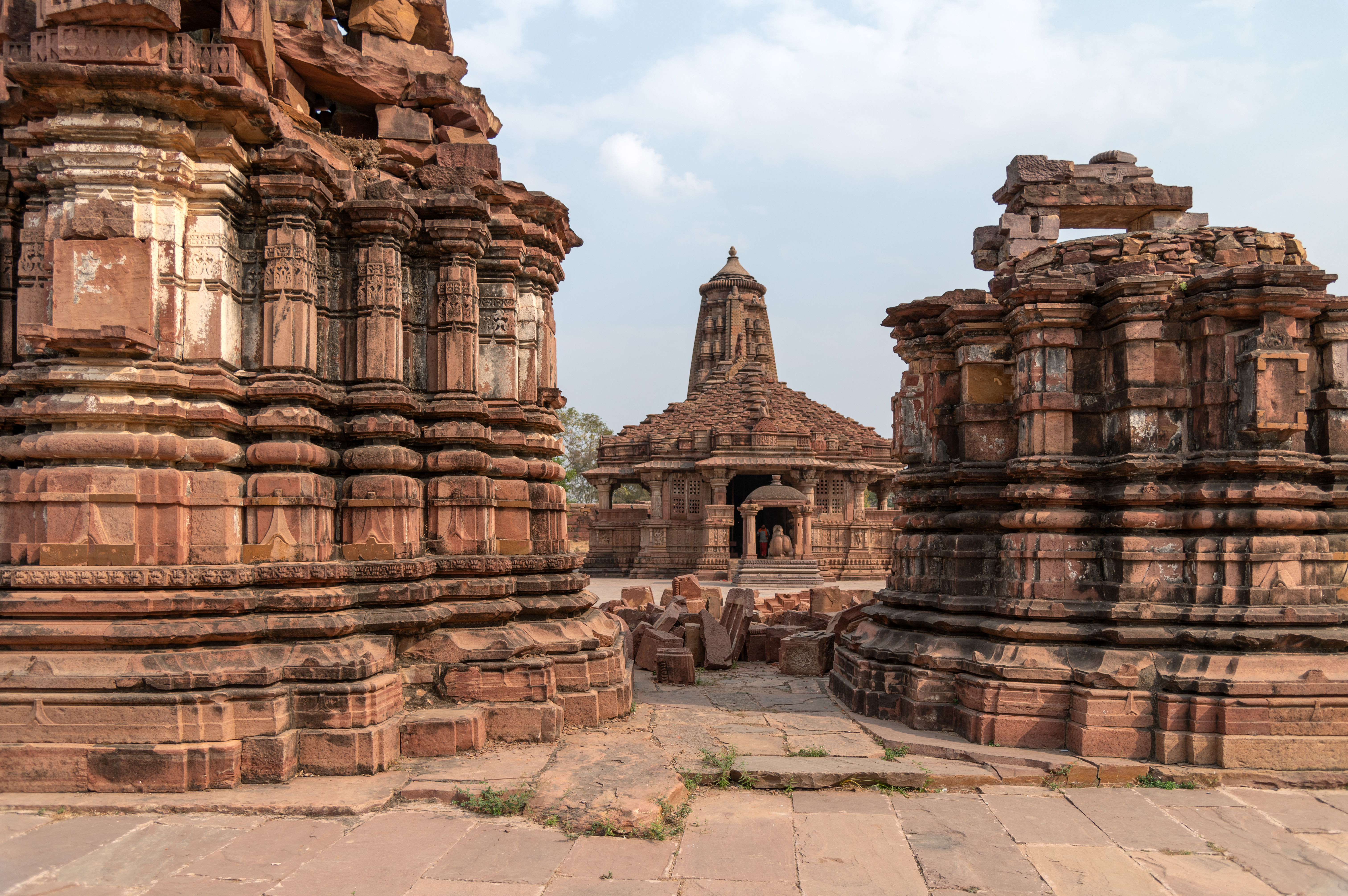 View of the west facing elevations of the two shrines facing the Mahanaleshwar Temple. These temples are built in red sandstone, consisting of plain plinth mouldings, geometric motifs on the wall subsidiary projections and deep niches in the principal projections.