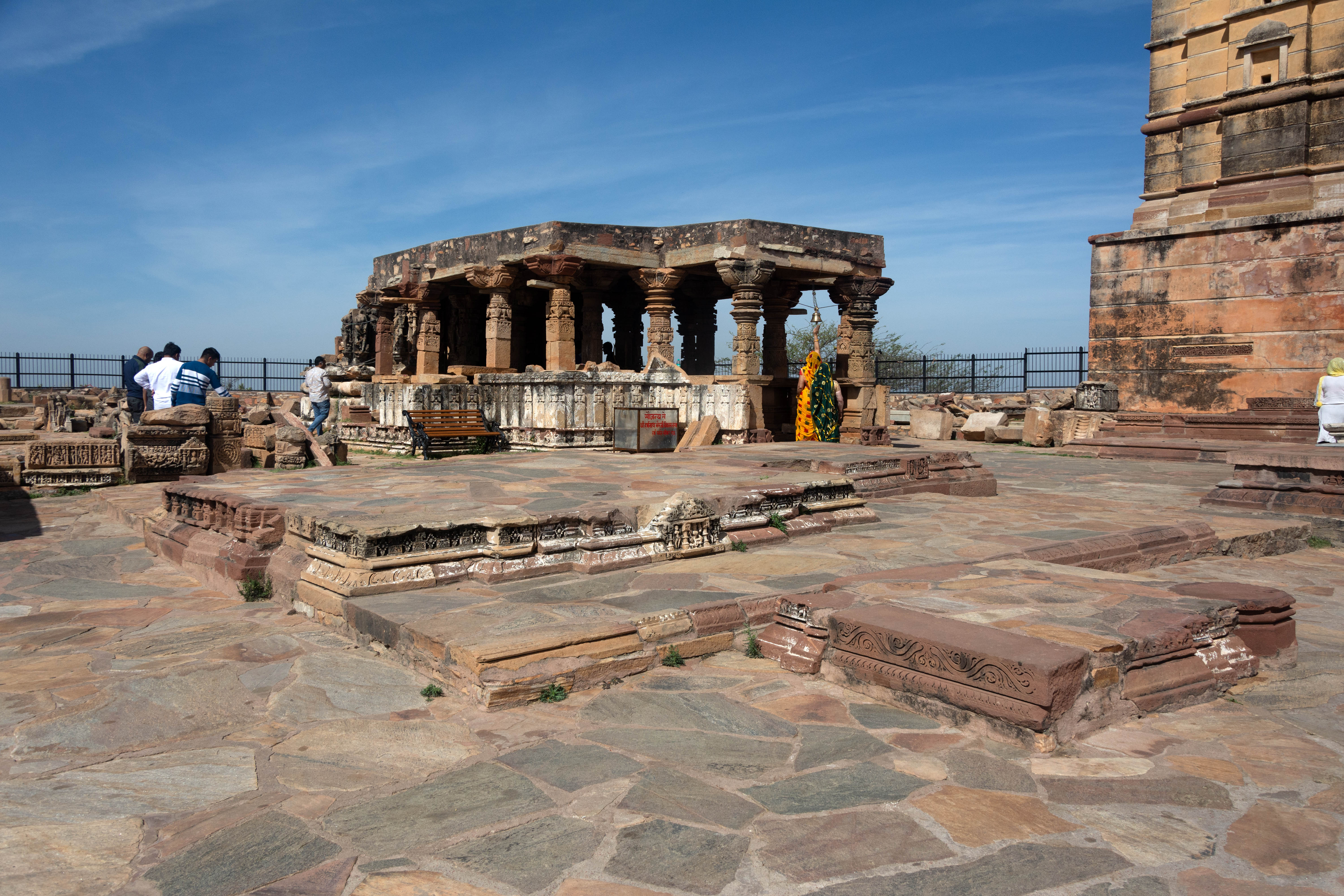 Image 1: The temple, now in a state of considerable ruin, consists of a mulaprasada of tri-anga specification, joined by a rangamandapa. It lacks the pitha but begins with a single plinth. Despite some damage, the vedibandha once featured a kumbha, adorned with intricate udgama motifs, and a small central box containing a figure. The jangha, now almost entirely ruined, had dikpalas at the karnas, as evidenced by remains in the northeastern corner. The surasundaris were possibly located at the pratirathas and the salilantara-recesses. Inside the sanctum is a shivalinga in active worship, which seems to be contemporaneous with the main shrine.