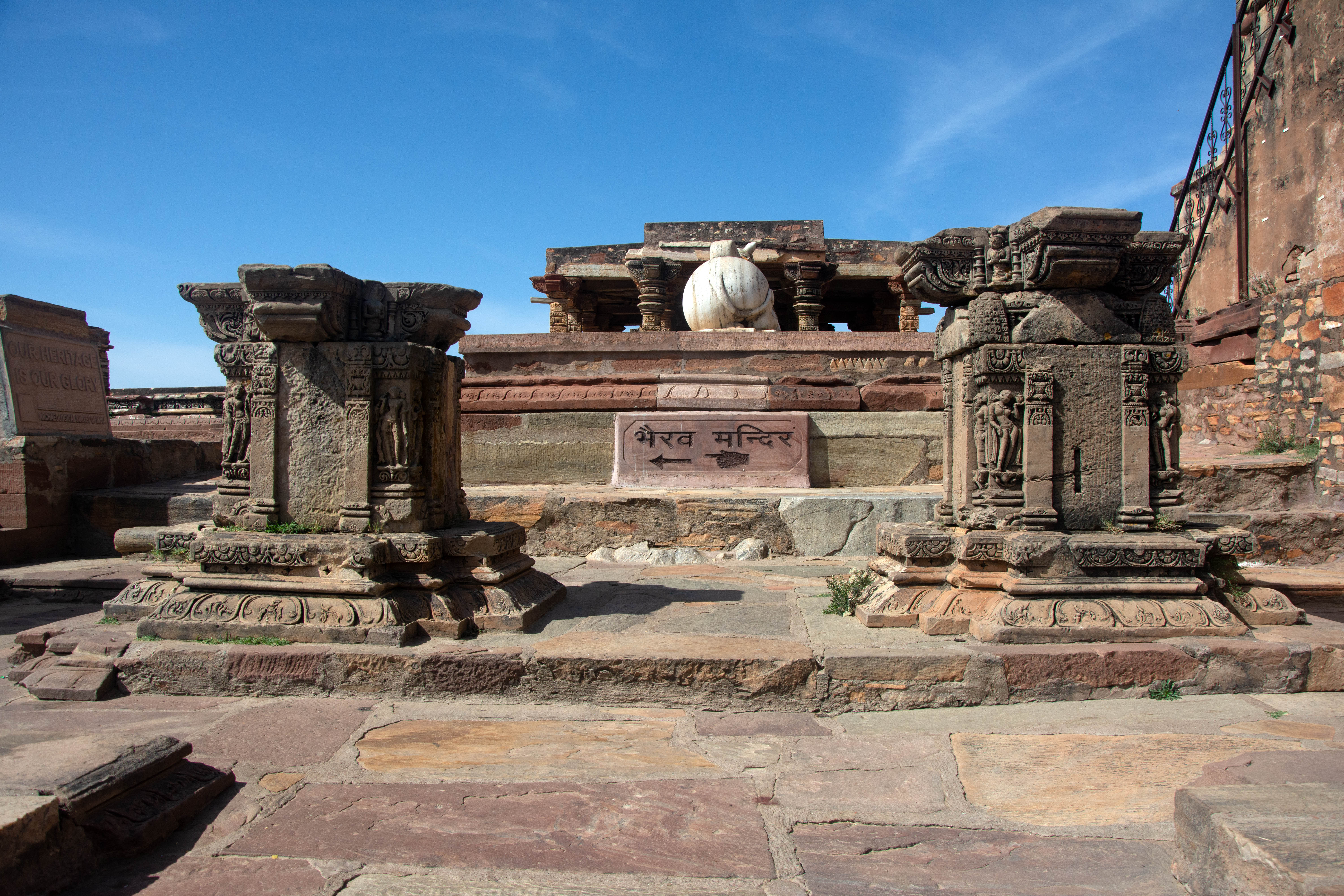 The temple complex's entrance was once adorned with the shafts of a pair of columns that surmounted a torana or doors. Verse 12 of the Harshnath stone inscription records, ‘Resembling (in height) the peak of Meru, it is pleasant on account of an excellent torana-dvara (arched doorway) and well-carved Nandi, and is full of manifold objects of enjoyment.’