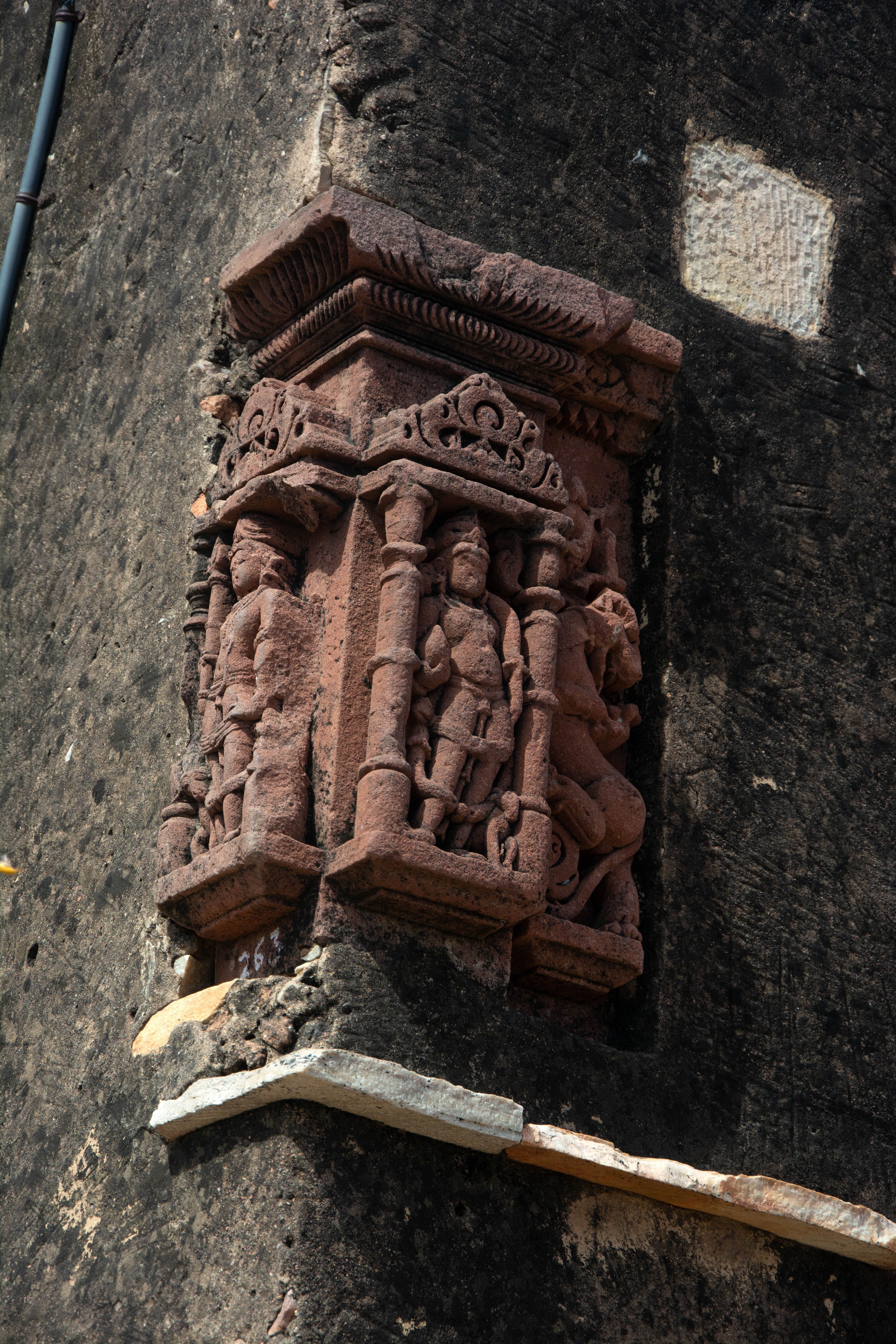 The right-hand side's niche depicts the dikpala, or directional deity, Kubera, while the adjacent figure on the left represents Ishana. The subsidiary offset of the temple wall depicts Vyala. The image of a directional deity that once adorned the temple wall is now affixed to a late mediaeval structure on Harsha Hill.