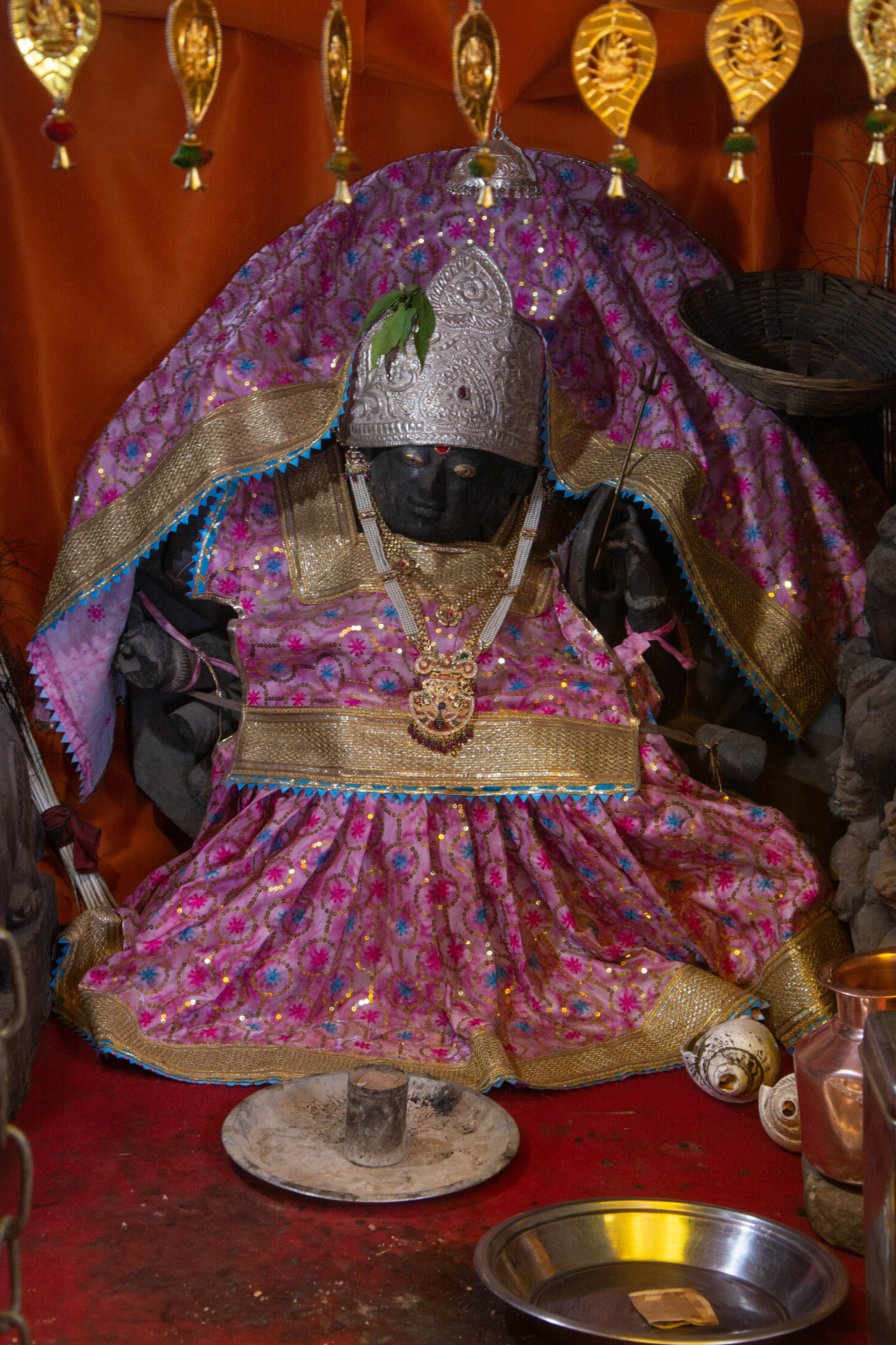 Outside the entrance of the Harsha Bhairon shrine on Harsha Hill, this image of Durga-Mahishasuramardini is in active worship. Black paint and clothing have obscured the image's details. It is one of the many images contemporaneous to the Harsha shrine, affixed in the enclosure of the Bhairon shrine.