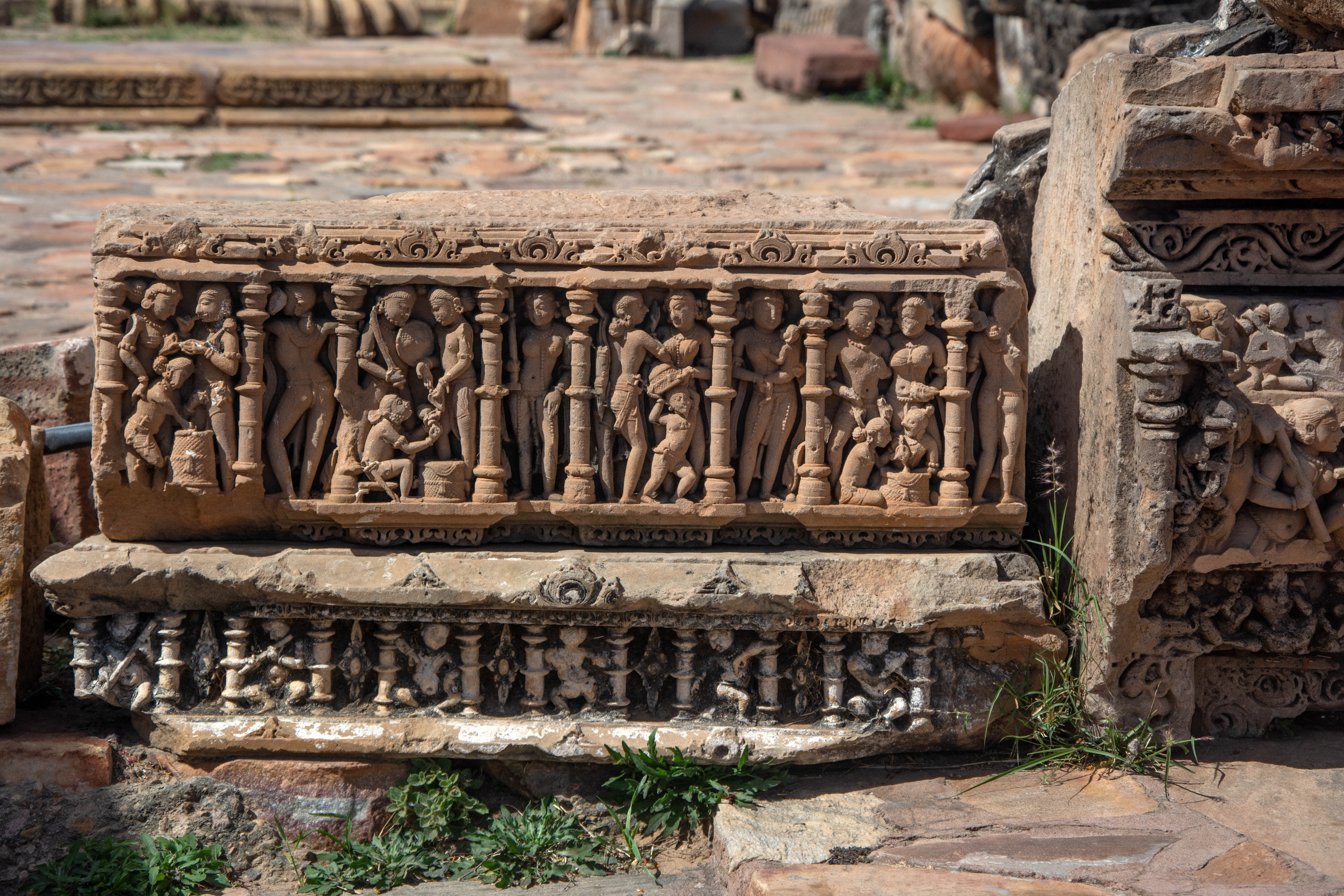 It appears that the beam, which was richly carved with human figures, was likely placed on the temple's varandika, the adjoining portions between the temple walls and the spire. Typically, the protruding offsets showcase mithuna figures within the niches, while the recess between the two offsets showcases exquisite carvings of apsaras or women performing various actions like carrying children or weapons.