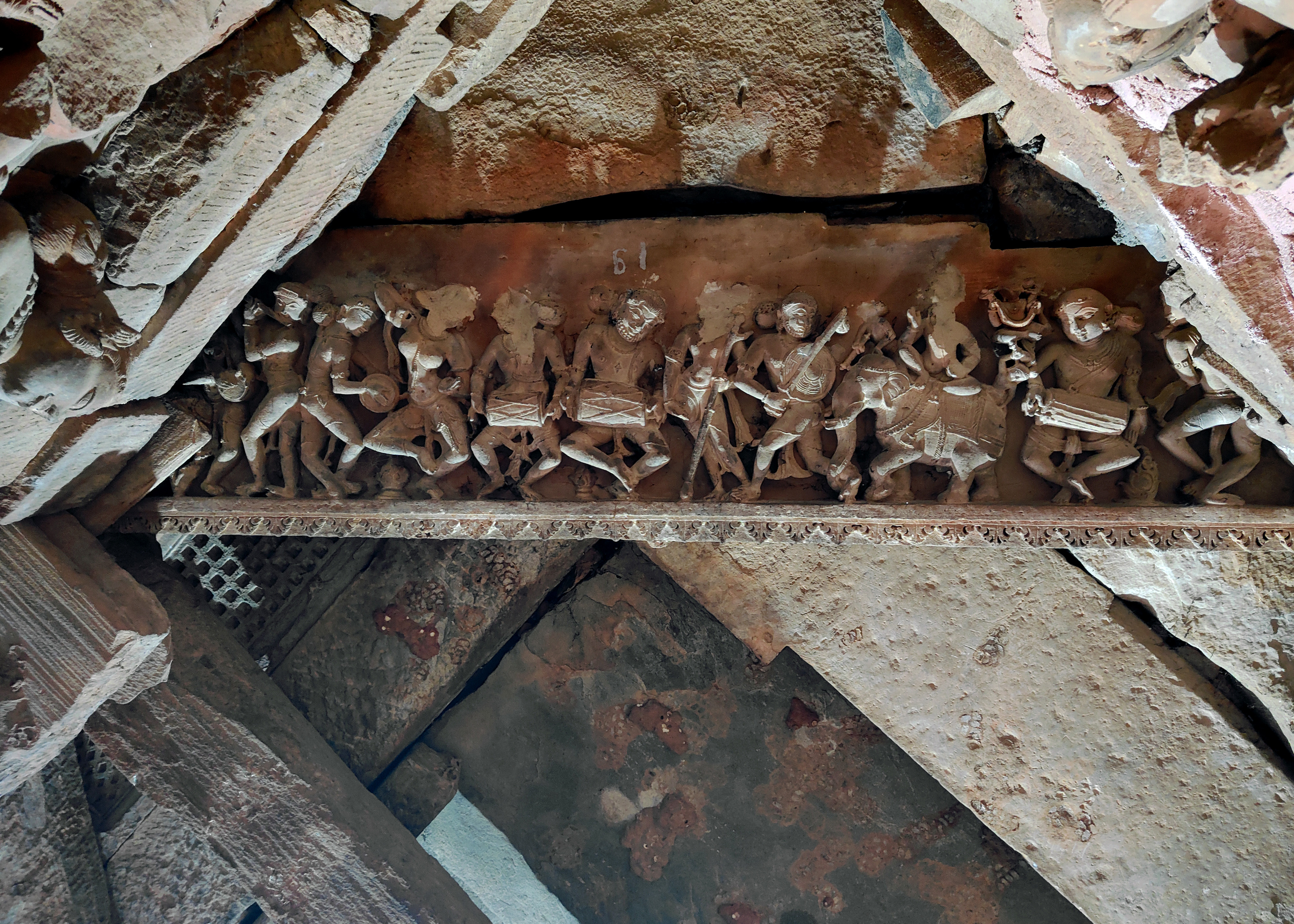 Indra is seated on his elephant Airavata in the frieze (of the ceiling of the Harshnath Temple sanctum) of the drumming and dancing gods, accompanied by a warrior holding a sword, shield, and an apsara. This image aligns with verse 7 of Vigraharaja II's Harsha stone inscription, stating that a joyous divine host, Indra, worships the Lord Harsha (Shiva) on the hill.