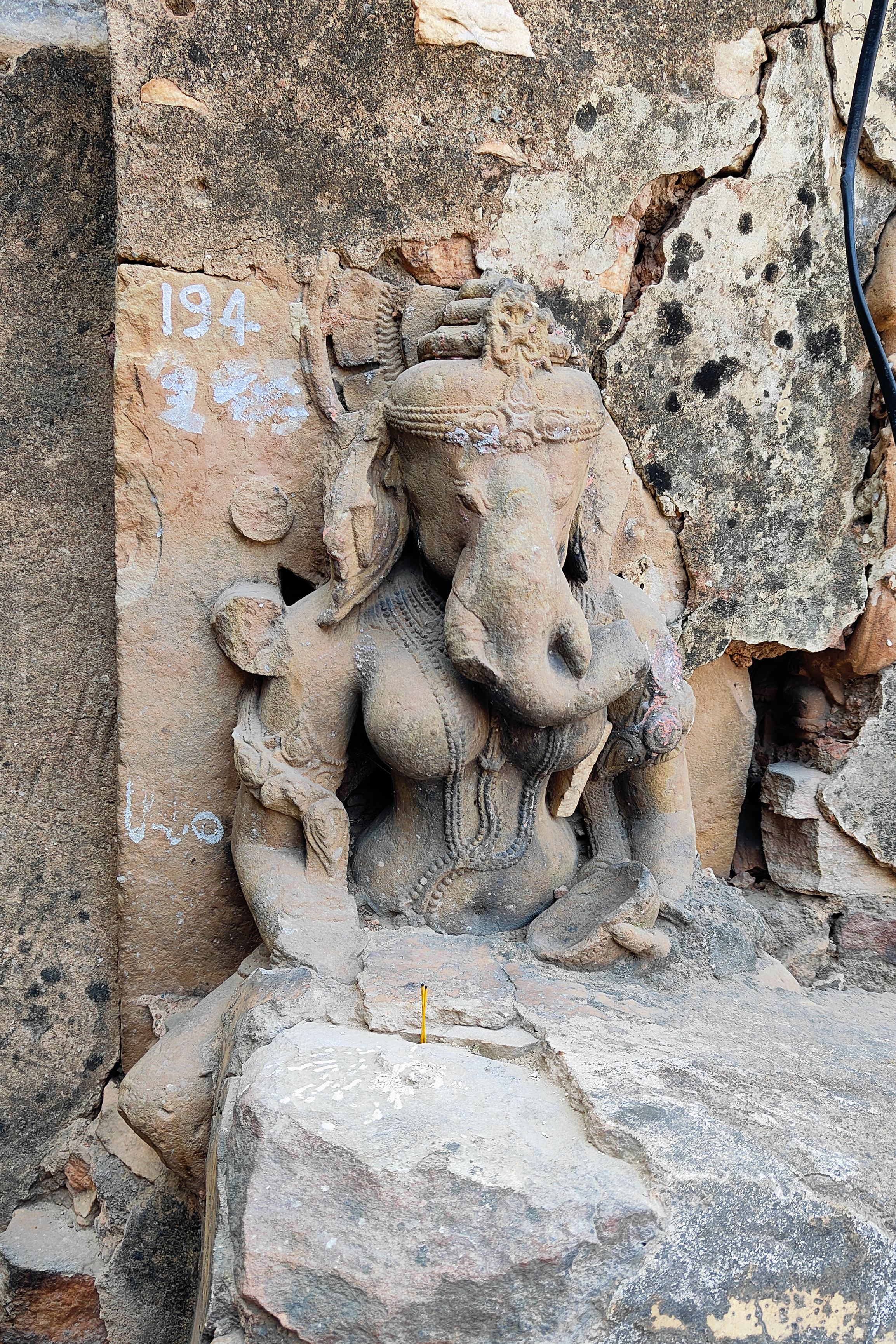 This is a rare image of Vinayaki, the feminine aspect of Vinayaka or Ganesha (consort in some traditions). The stairs built next to it have subsumed the lower portion, leaving only a partial image visible. Many of the Shaiva and Shakta images at the site feature her holding a cup in one of her hands, a characteristic associated with the tantric tradition.