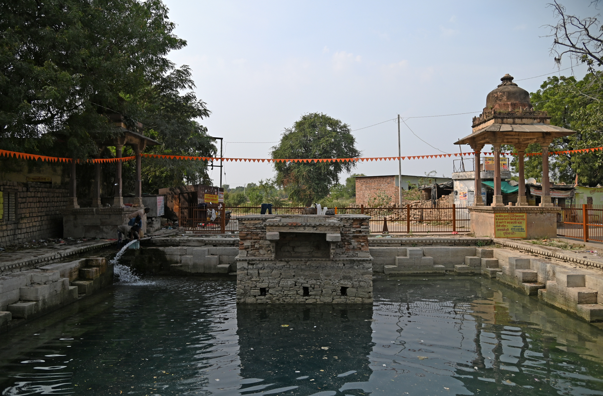 In front of the temple lies a water tank, seemingly a later addition, as indicated by the presence of chhatris installed at its corners. Steps lead down to the water level. There is a raised platform on one side. The locals regularly use the tank for various purposes.