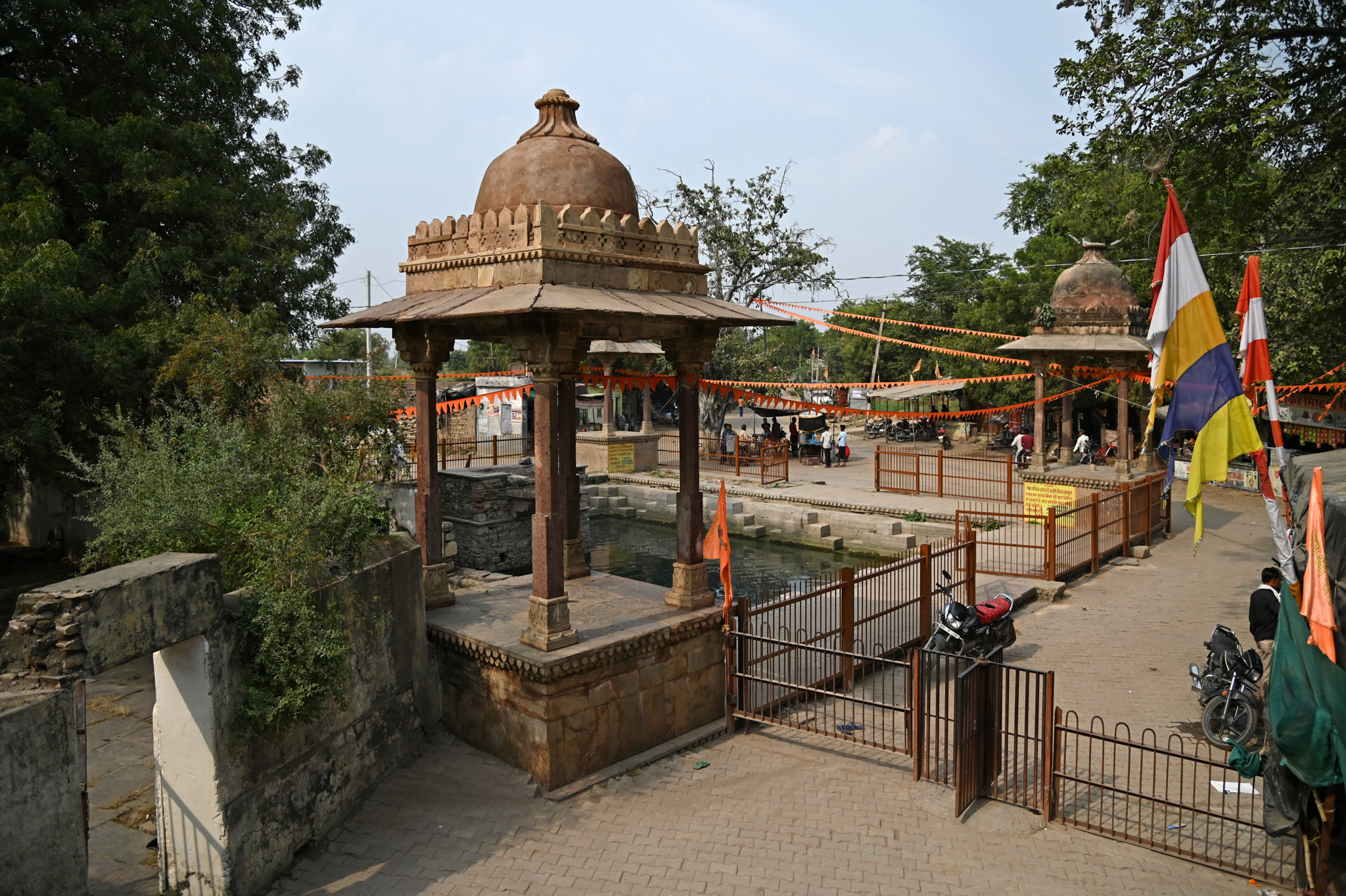 The temple provides a view of the water tank, featuring chhattris at its corners. The sandstone chhatris, a square platform with four pillars topped by a cupola, is a later addition.
