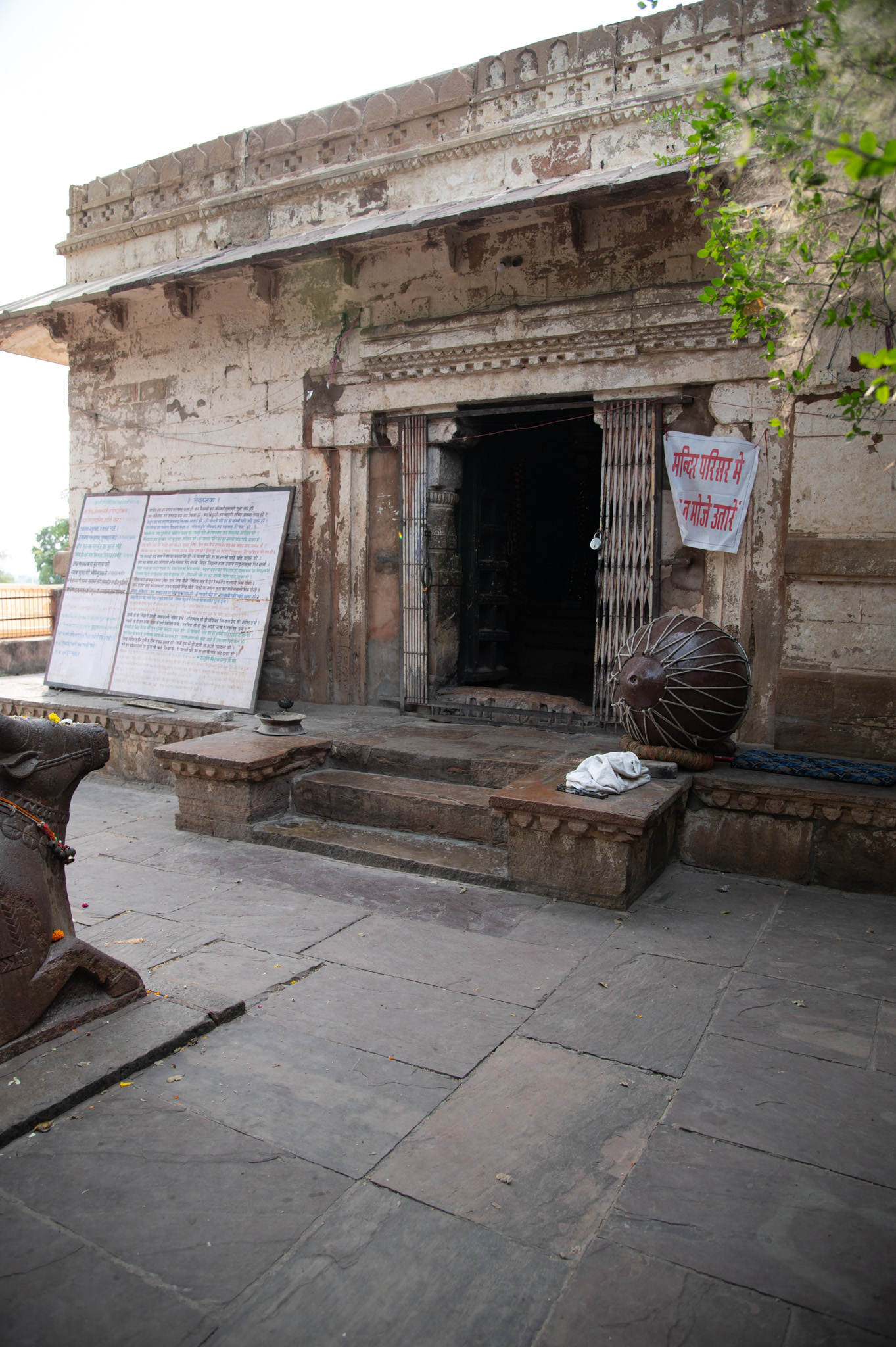 The east-facing entrance leading to the mulaprasada has a plain and simple base, with a few steps paving the entrance, and a single decorative band at the top. The front façade is plain, with a flanking chhajja supporting the roof.
