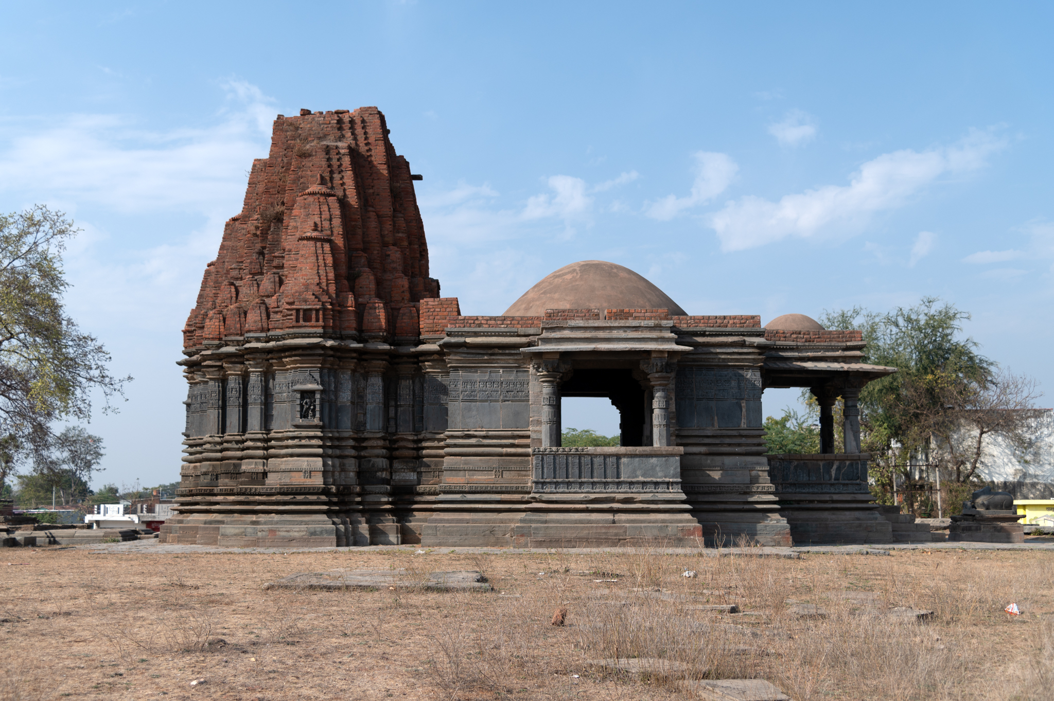 Mandaleshwar Mahadev Temple's south-facing elevation can be seen here. The temple’s plan consists of a mukhamandapa (front porch) followed by a mandapa (pillared hall), an antarala (antechamber), and a garbhagriha (sanctum sanctorum). The mandapa is semi-open, meaning that it has lateral wings or transepts on the south and north sides. The original shikhara (superstructure) of the temple is probably lost. Presently, the temple has a shekhari (multi-spired) variety of shikhara built in brick.