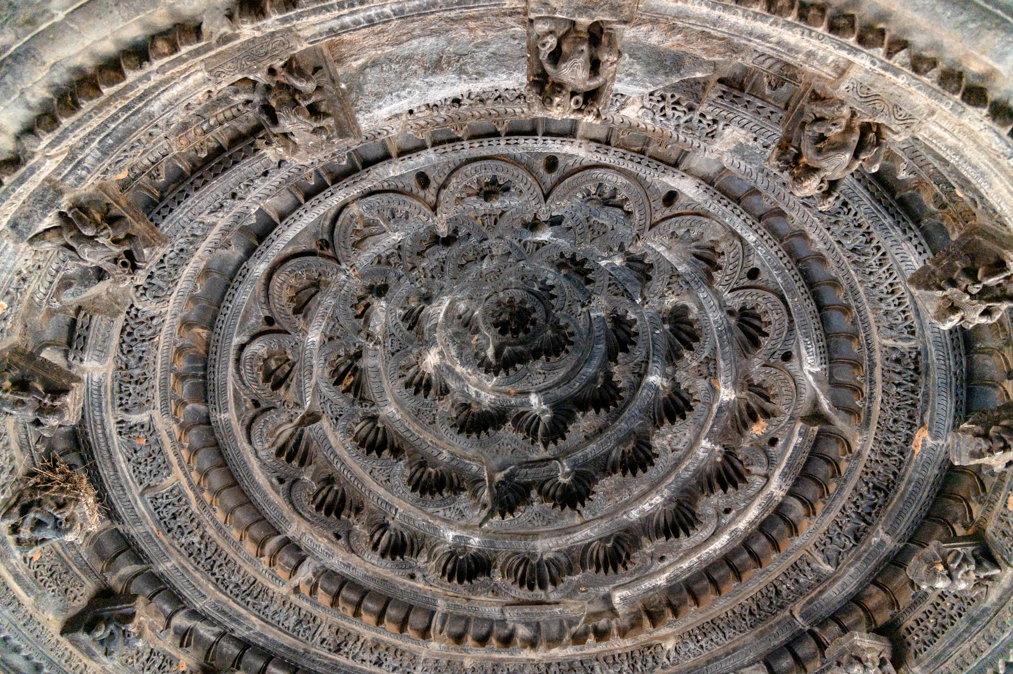 The domical (vitana) ceiling of the Mandaleshwar Mahadev Temple is intricately carved. Concentric circular rings made of cusps or fractals form the ceiling. The lowermost ring has sculptured brackets. The first rings of the ceiling have kirtimukha (face of glory) motifs and a row of small sculptures. Semi-circular floral fractals make up the inner rings.