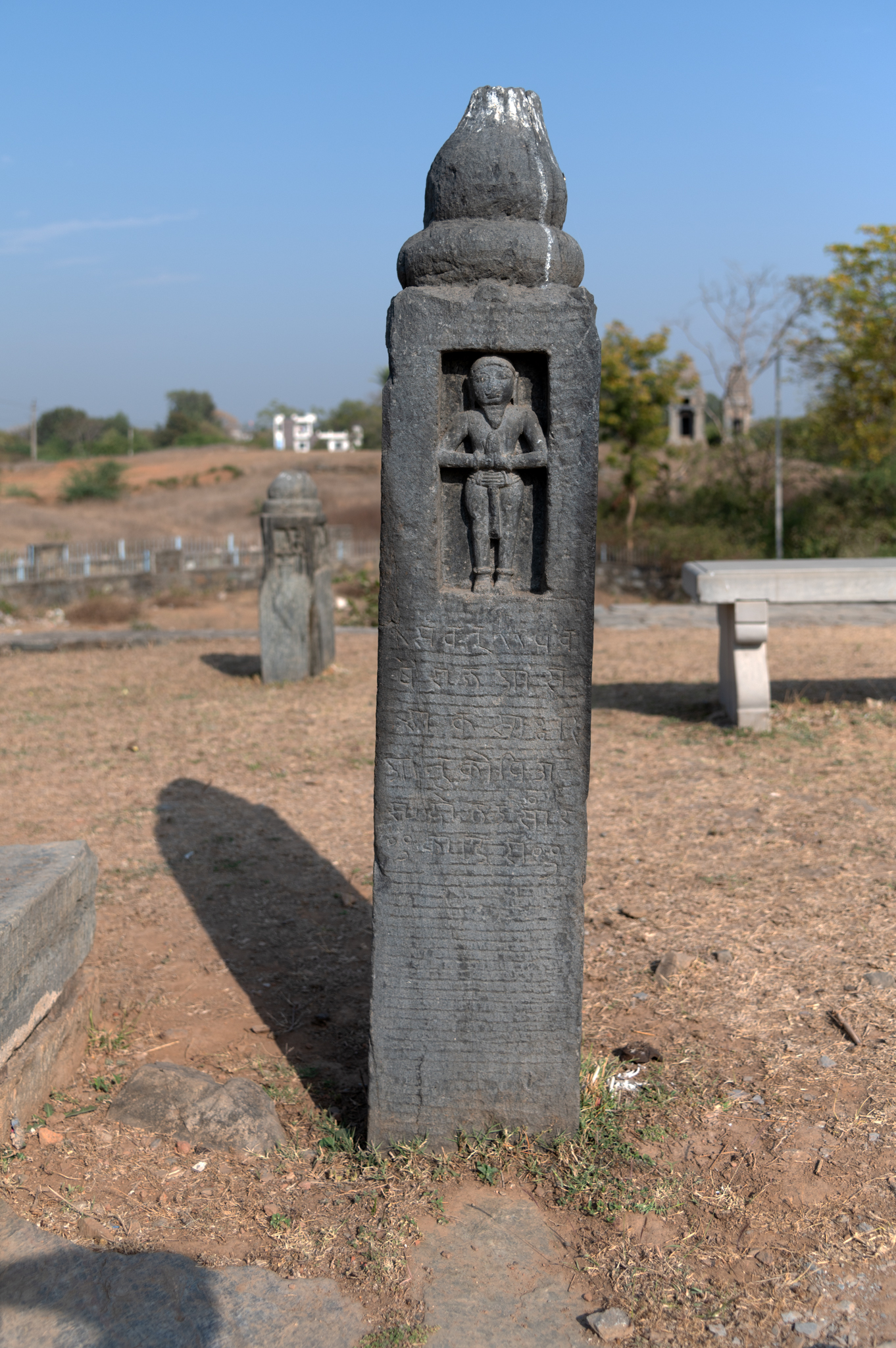 These memorial stones are found in an open space in front of the Mandaleshwar Mahadev Temple. Below the depiction of the human figure, there are a few inscription lines. The inscription is in the Sanskrit language and Devanagari script.