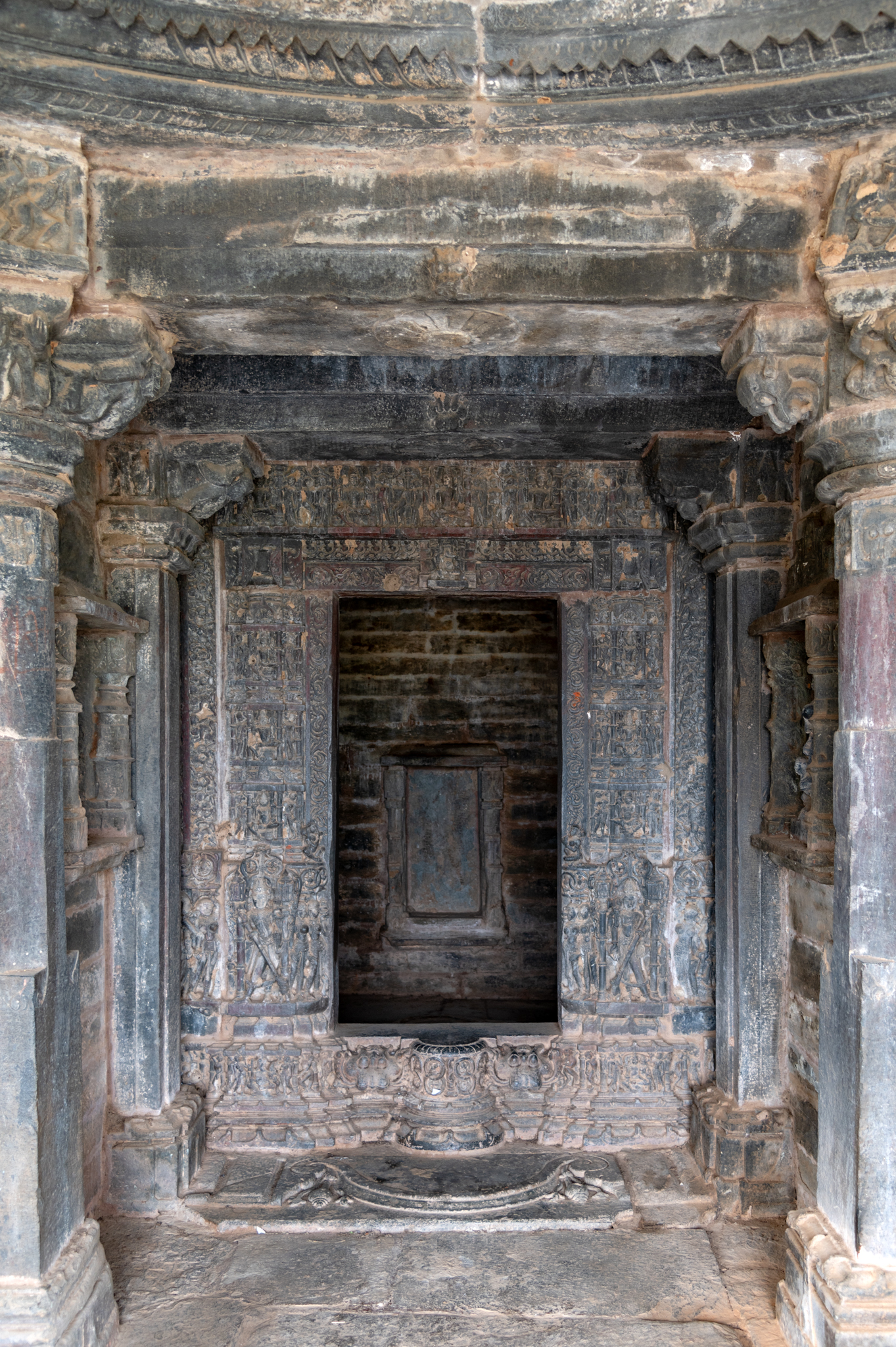 An ornate dvarashakha (door jamb) marks the entrance to the garbhagriha (sanctum sanctorum) of the Someshwar Mahadev Temple. The uttaranga (top band) of the dvarashakha and the vertical divisions flanking the opening have depictions of deities like Shiva, Mahesh, Brahma, and goddesses.