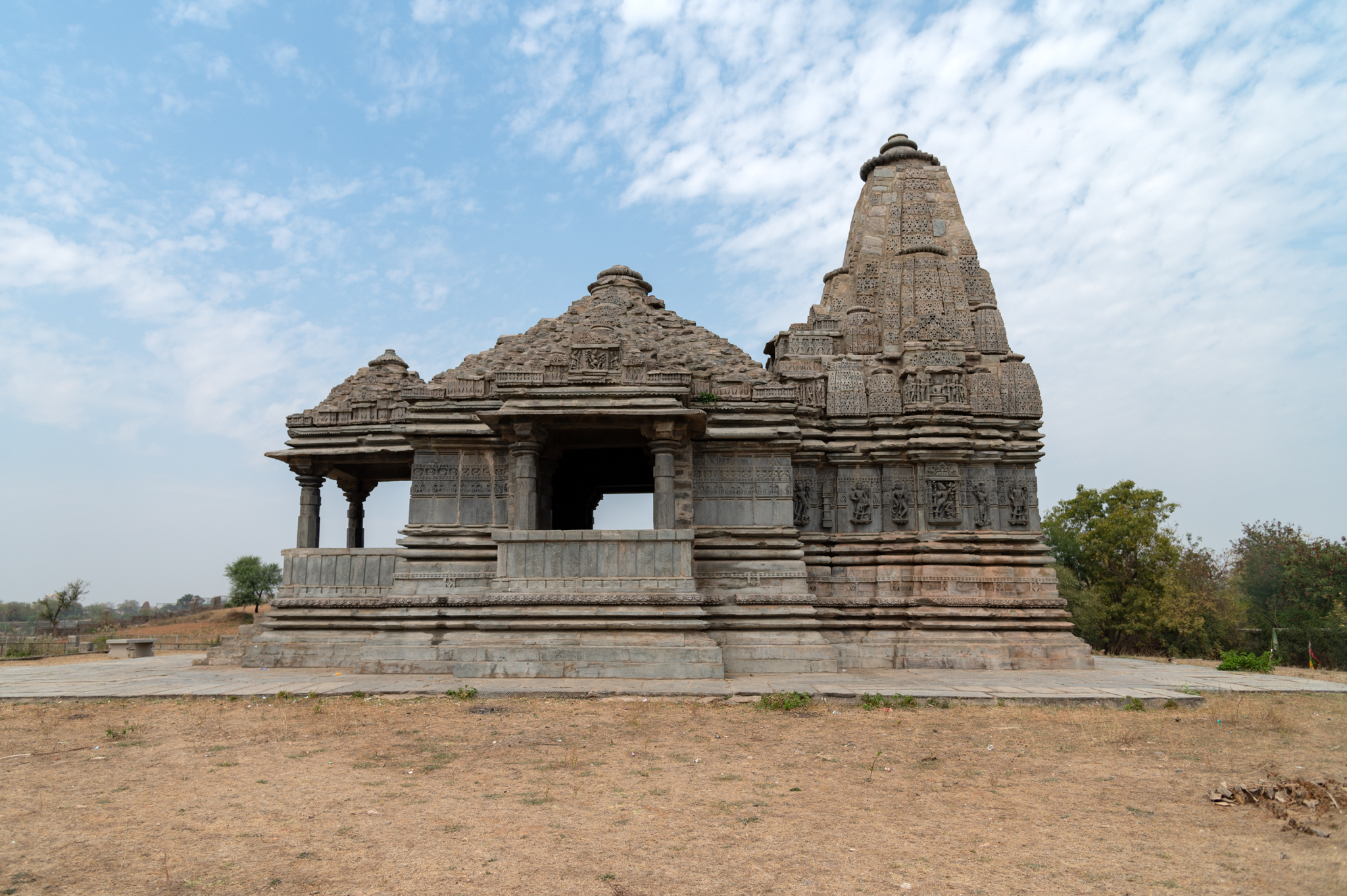 This is the south-facing elevation of the Shiva Temple, from the Arthuna group of temples. According to its plan, the temple consists of a mukhamandapa (front porch), a mandapa (pillared hall), an antarala (vestibule or antechamber), and a garbhagriha (sanctum sanctorum). Above the garbhagriha rises a lofty shekhari (multi-spire) shikhara. This is the only temple with a complete, renovated shikhara. The exterior temple structure has undergone several restorations. They have reassembled many of the fallen architectural elements.