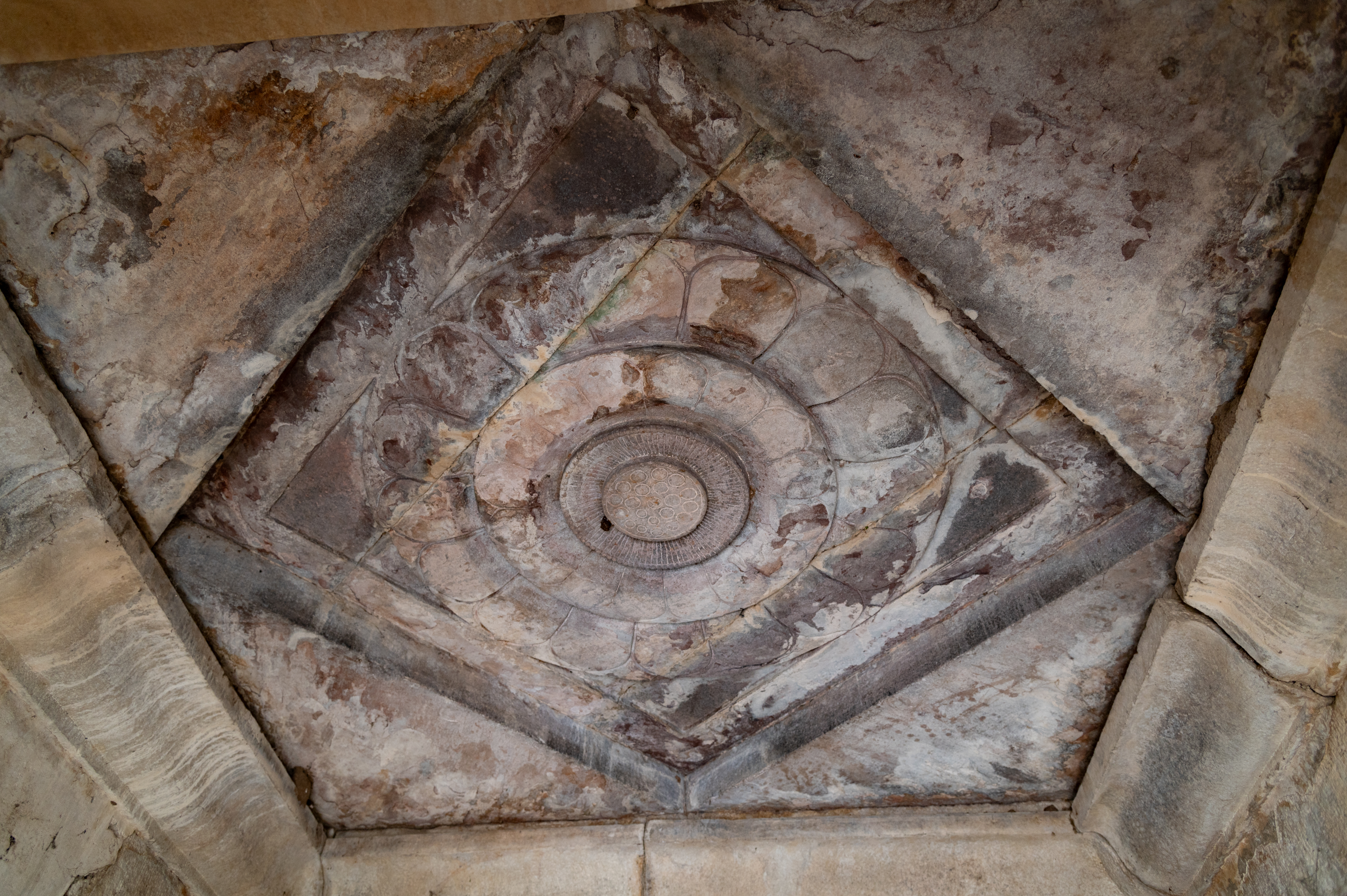 The garbhagriha (sanctum sanctorum) of the Shiva Temple (Temple 1) in Cluster 1 is a plain square chamber with a carved ceiling. The ceiling shows a full-blown flower with layered petals enclosed within a square frame.