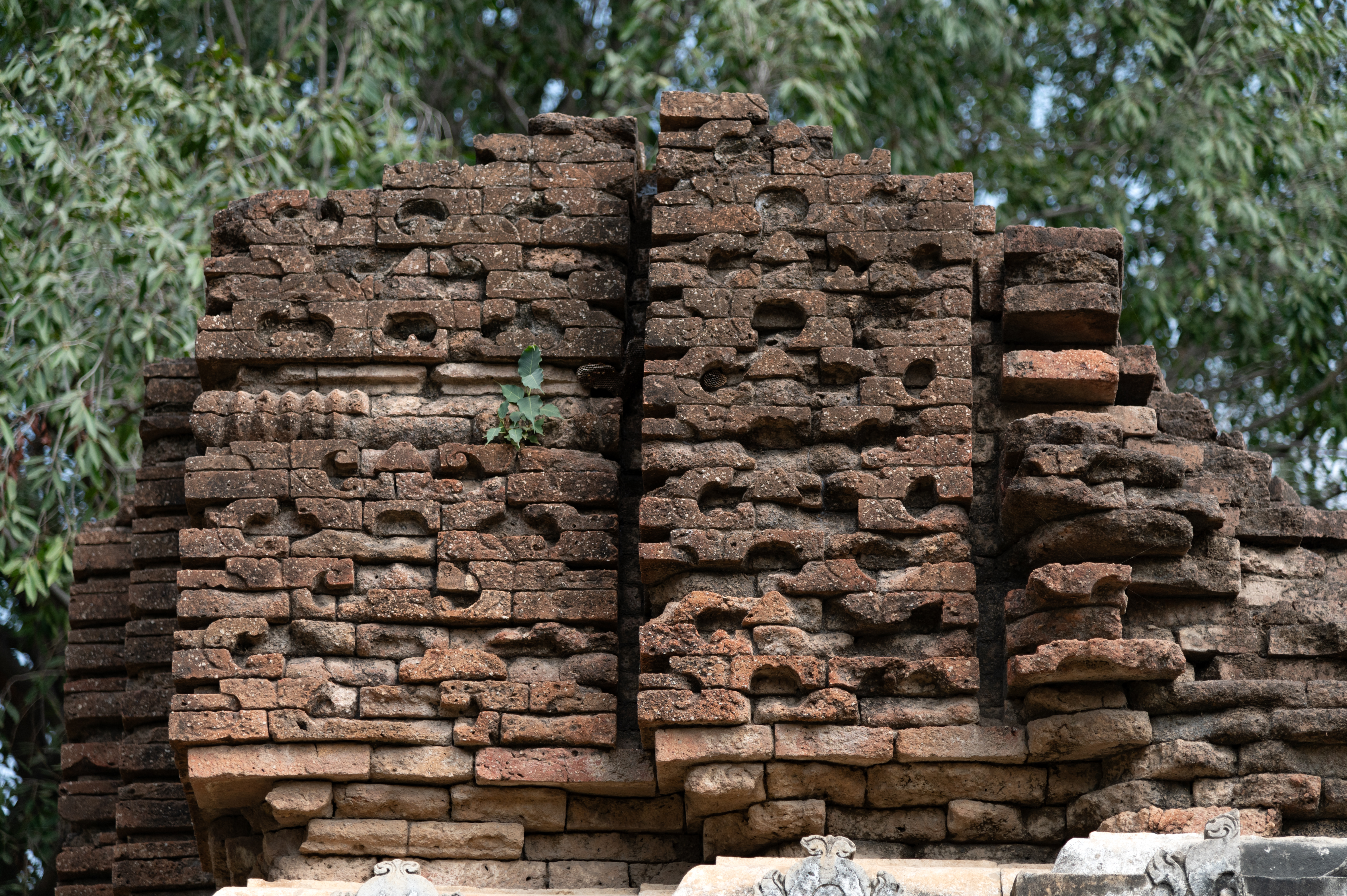 The shikhara (superstructure) of the Shiva Temple (Temple 1) in Cluster 1 is deteriorating, with a portion having already collapsed. The remaining part reveals brickwork with the chaitya (dormer window) arch design.