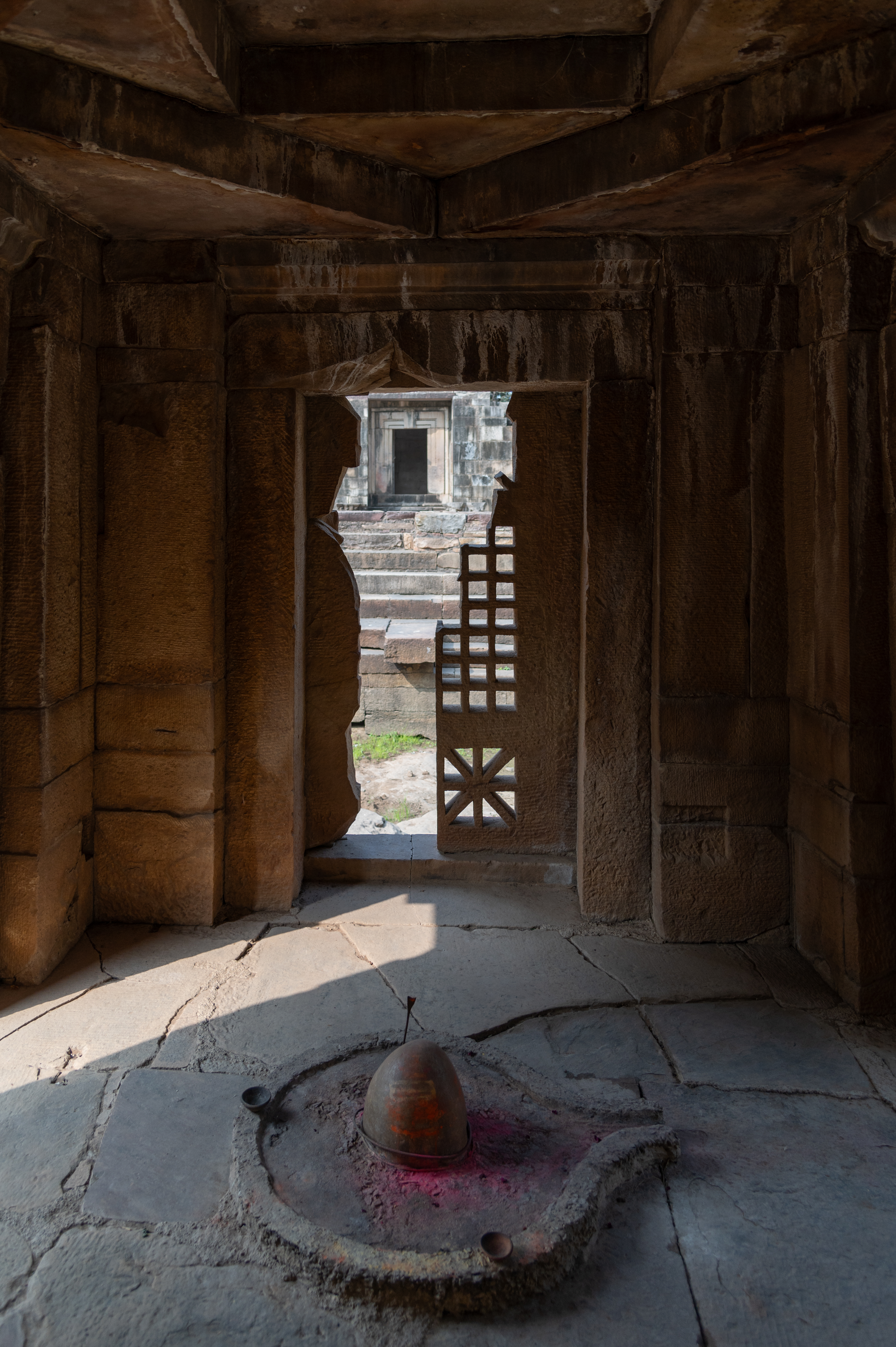 The garbhagriha (sanctum sanctorum) of the Shiva Temple (Temple 3) is a small square structure housing a Shiva linga at the centre. The rear wall is closed by a screen, which is also broken. The ceiling of the sanctum is also simple, featuring a square within a square.