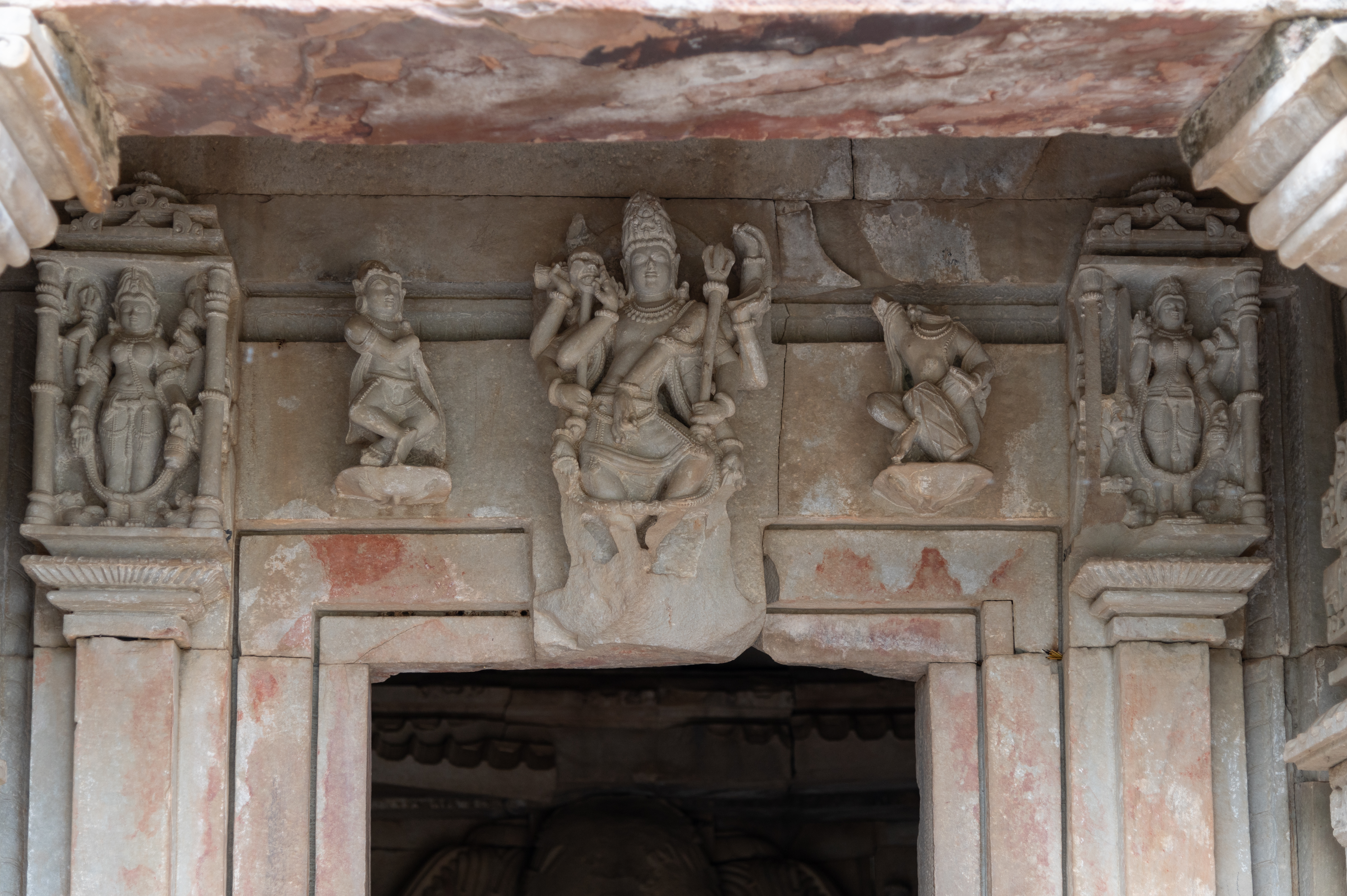 The lintels above the shakhas (vertical bands) of the Sadashiva Temple depict a dancing Shiva at the centre accompanied by a musician and a dancer. Goddesses are shown on the extreme ends. Shiva is portrayed as ten-armed, holding an akshamala (rosary), khatvanga (staff with a skull), damaru (drum), snake, kapala (skull), and trishula (trident), with his front two arms making dance a gesture. The goddesses are depicted as four-armed, wearing a jatamukuta (a crown of matted hair). They hold an akshamala and kamandalu (water pot), while their other hands hold their respective attributes.