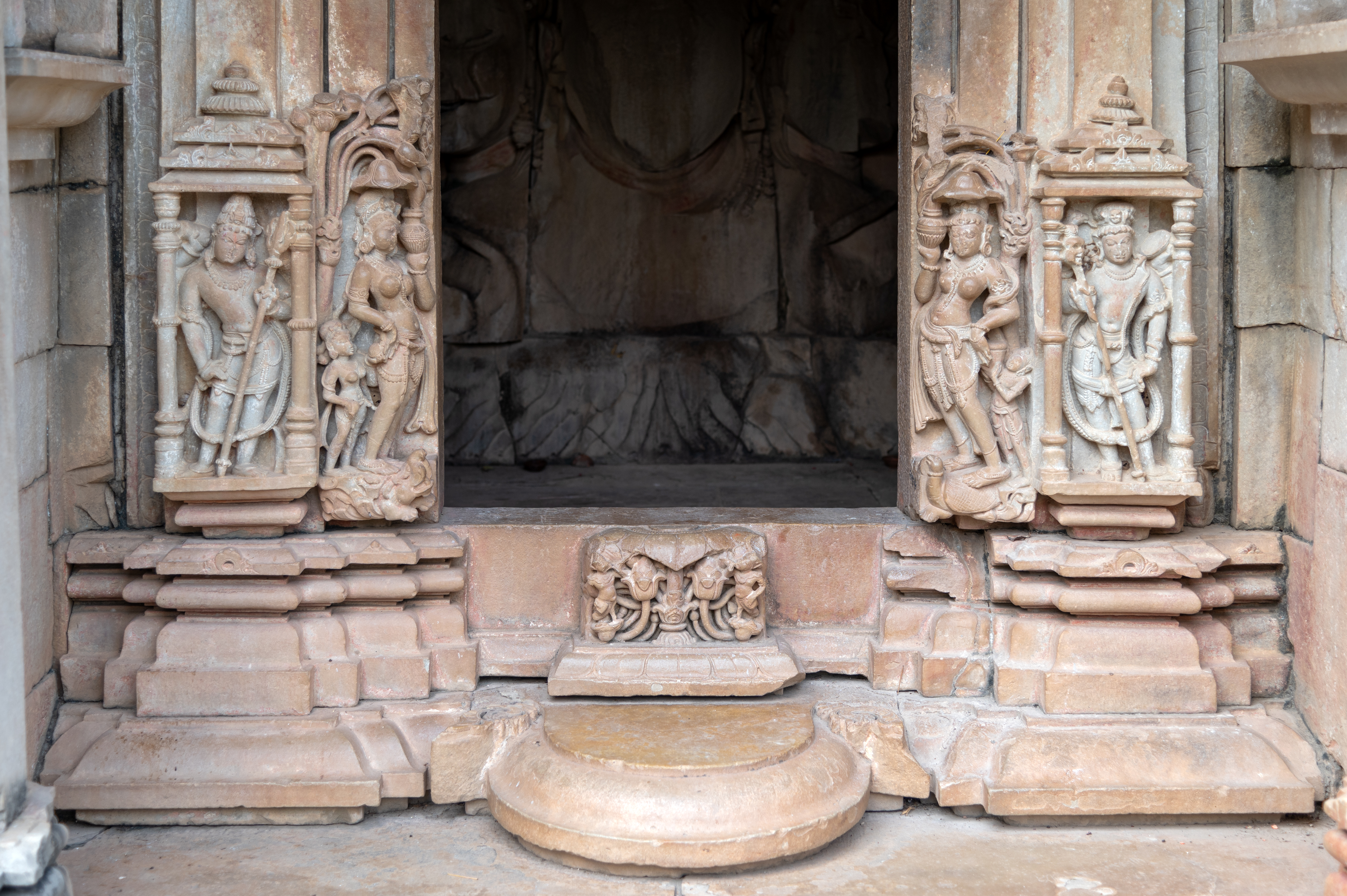 The entrance gate to the garbhagriha (sanctum sanctorum) of the Sadashiva Temple features plain shakhas (vertical bands), while the bottom part depicts river goddesses Ganga and Yamuna, as well as Shiva dvarapalas (door guardians). Ganga is shown on the proper right, holding a water pot, standing on her vahana (mount), a makara (crocodile). Yamuna is shown holding a water pot and standing on her mount, a kachhapa (tortoise). The dvarapalas are depicted holding weapons.