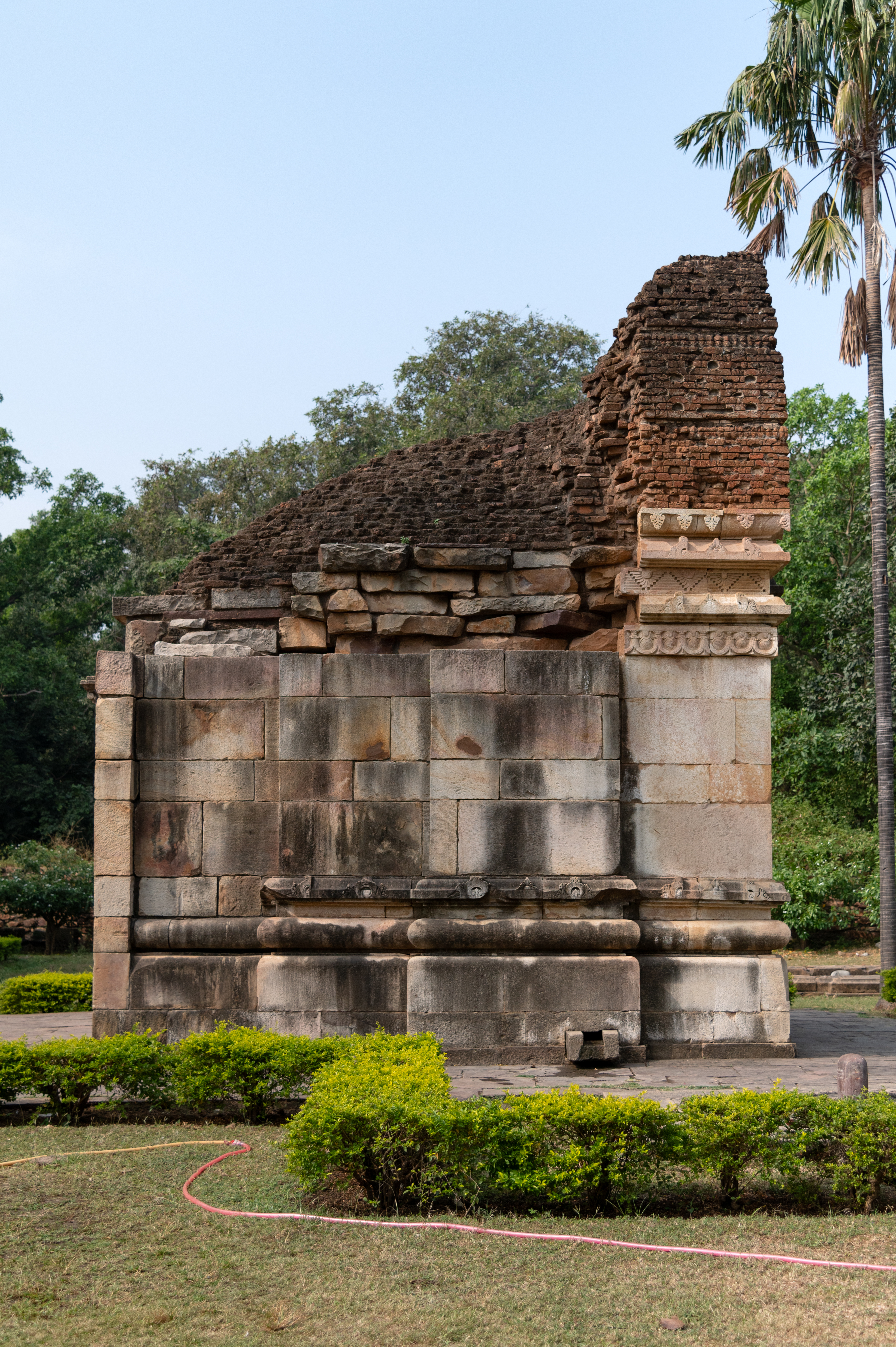 The temple features architectural elements such as khura, kumbha (pot-shaped), kalasha (a pitcher), and kapotapalikas (cyma recta moulding), upon which a plain jangha (wall) rises. Above the jangha, a varandika (moulded parapet) is placed which supports the shikhara (superstructure), adorned with bricks marked with chaitya arches.