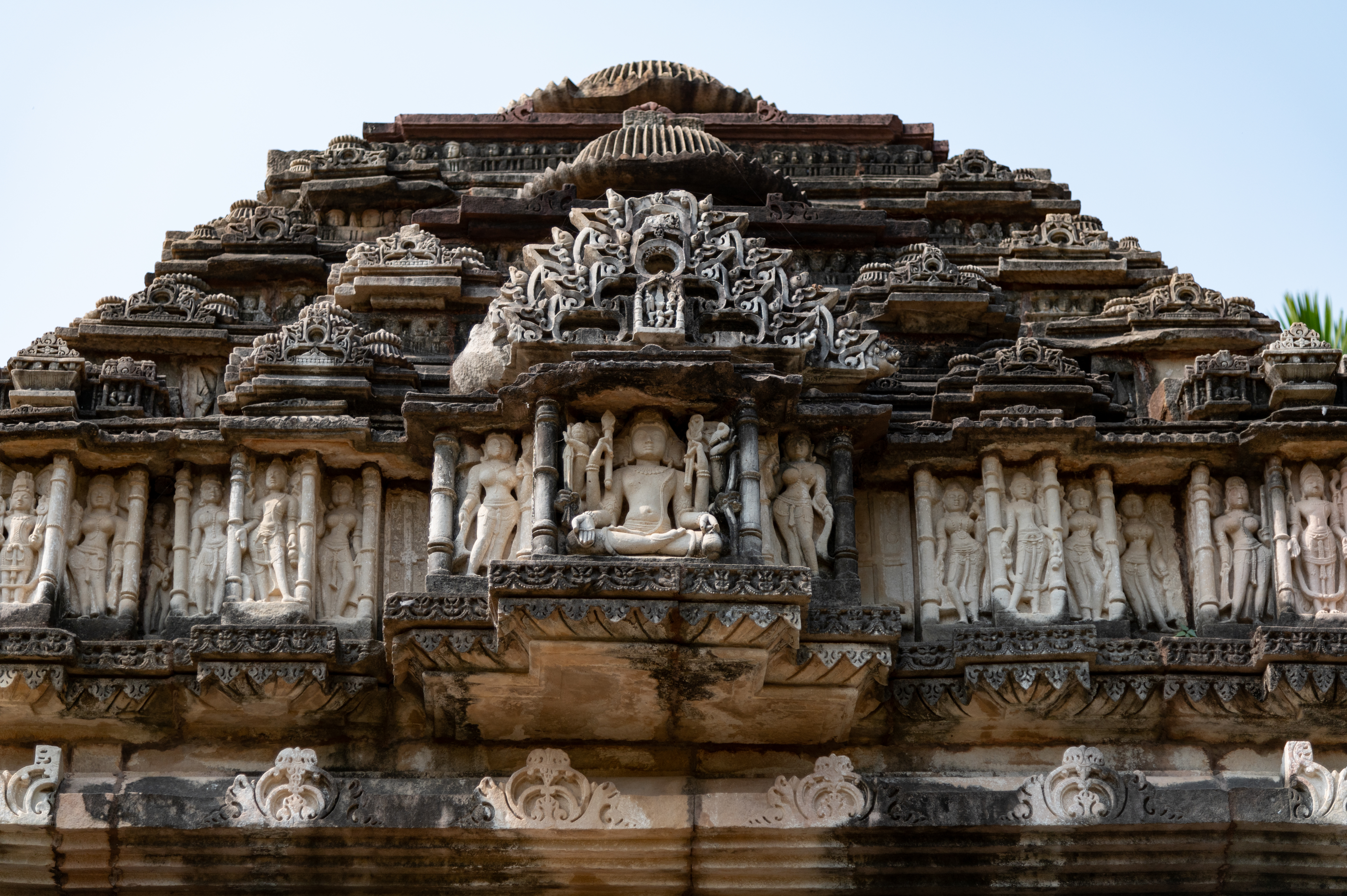 A beautiful sculpture of Kartikeya can be seen on the western pediment of the shikhara (superstructure) of the rangamandapa (open type of pillared hall). The God of war is depicted seated, with four faces, three of which are visible in the sculpture. He has eight arms and holds his weapons including a shakti/vel (spear), arrow and bow. He is holding a cork in one of his hands and his frontal hands are carrying an akshamala (rosary) and a kamandalu (water pot). The slender body of the young war god is adorned with jewellery and yajnopavita (sacred thread). It is one of the most beautiful representations of Kartikeya.