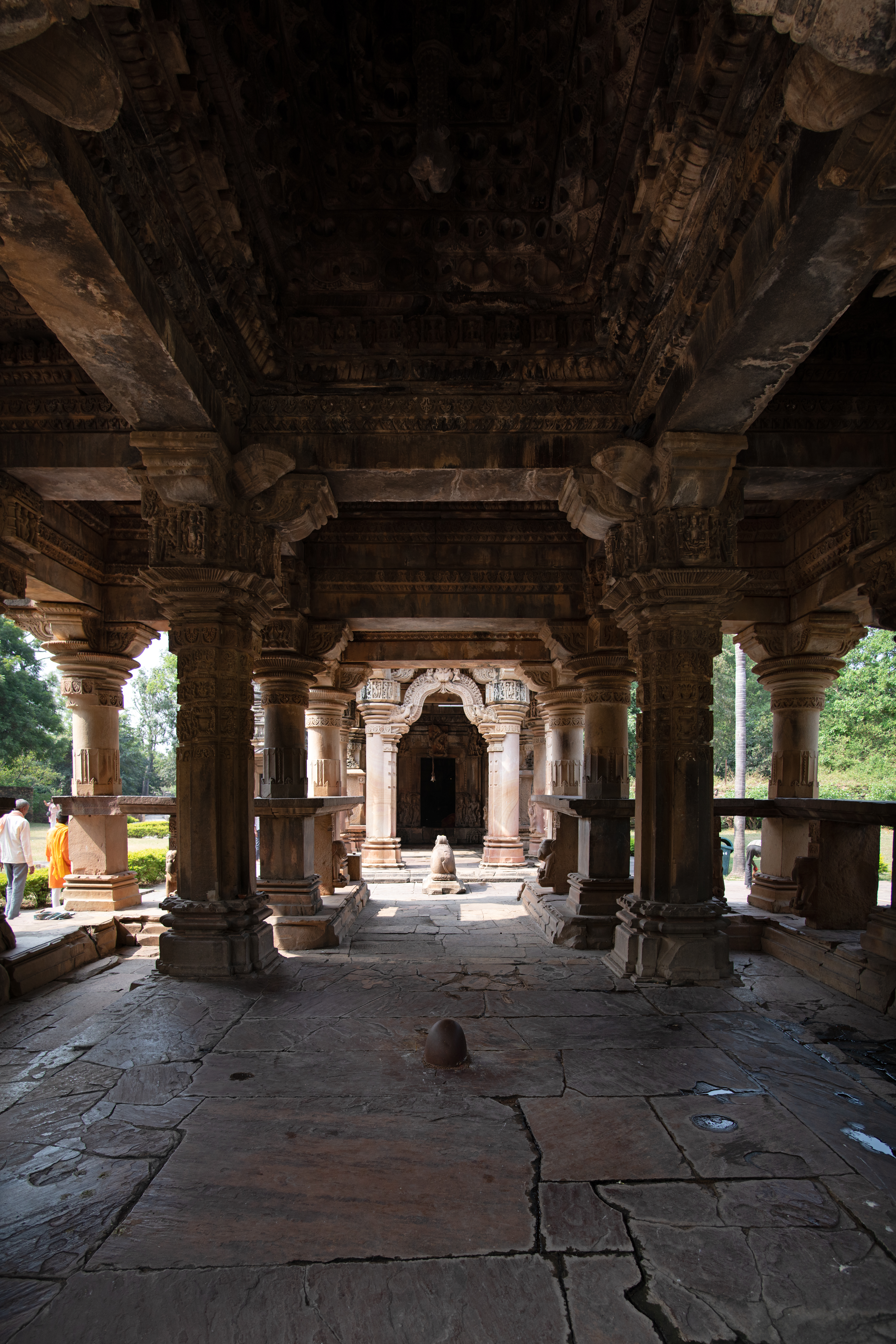 The rangamandapa (open type of pillared hall) is comprised of a multitude of heavy, ornately carved pillars that support the ceiling, crafted in two distinct styles. The outer pillars feature a square base which turns into faceted shapes and transitions into a circular shaft. In contrast, the innermost pillars maintain a square shape and depict deities on the panels at the top, supporting the brackets. There is a Shiva linga at the centre of the hall.