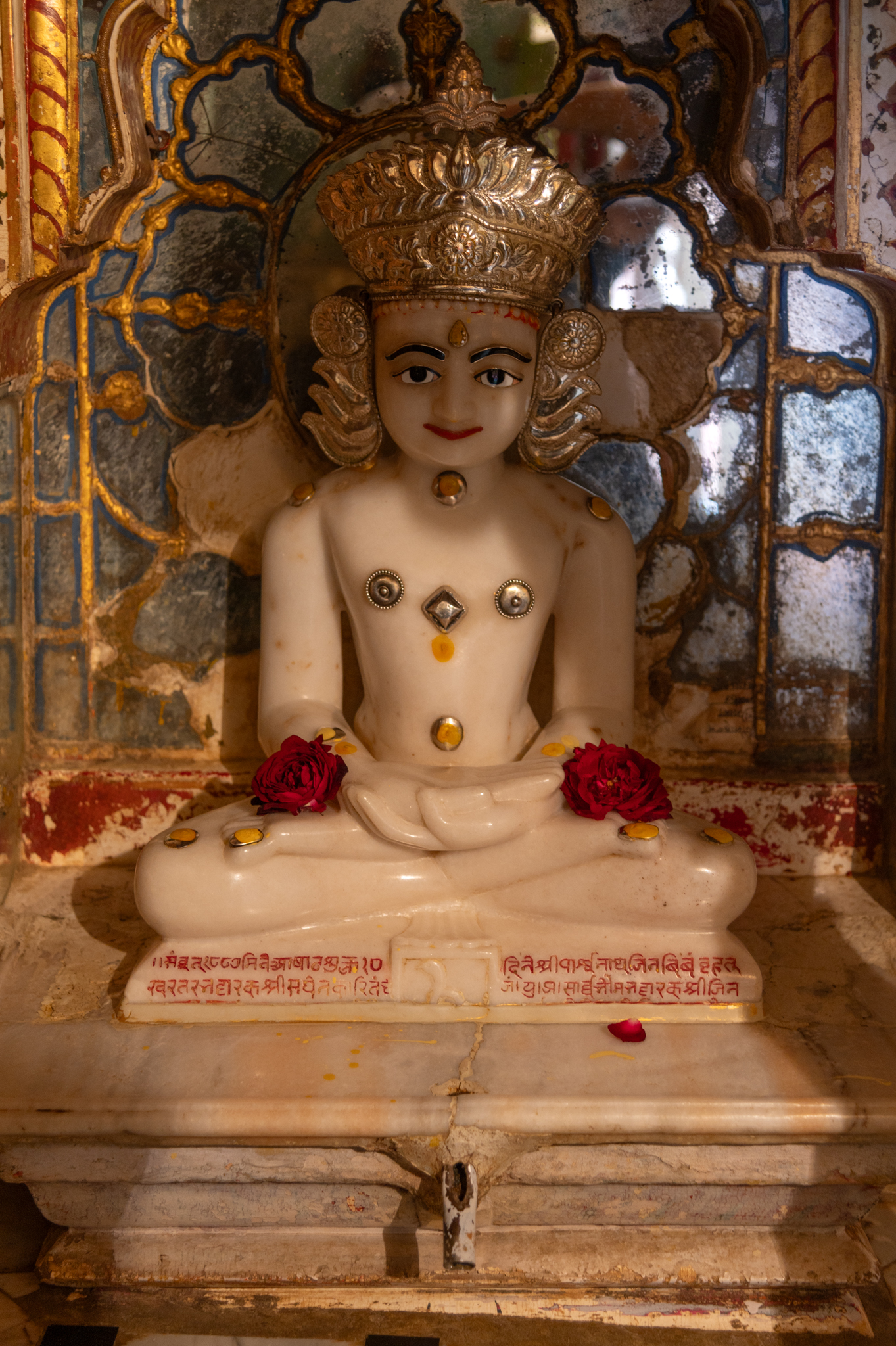 Sculpture of Parshvanatha Tirthankara in the garbhagriha (sanctum sanctorum) of the Adinatha Temple. Carved in marble, the Tirthankara is shown seated in padmasana (lotus pose) and dhyan mudra (meditation posture). The pedestal has a carving of a snake.