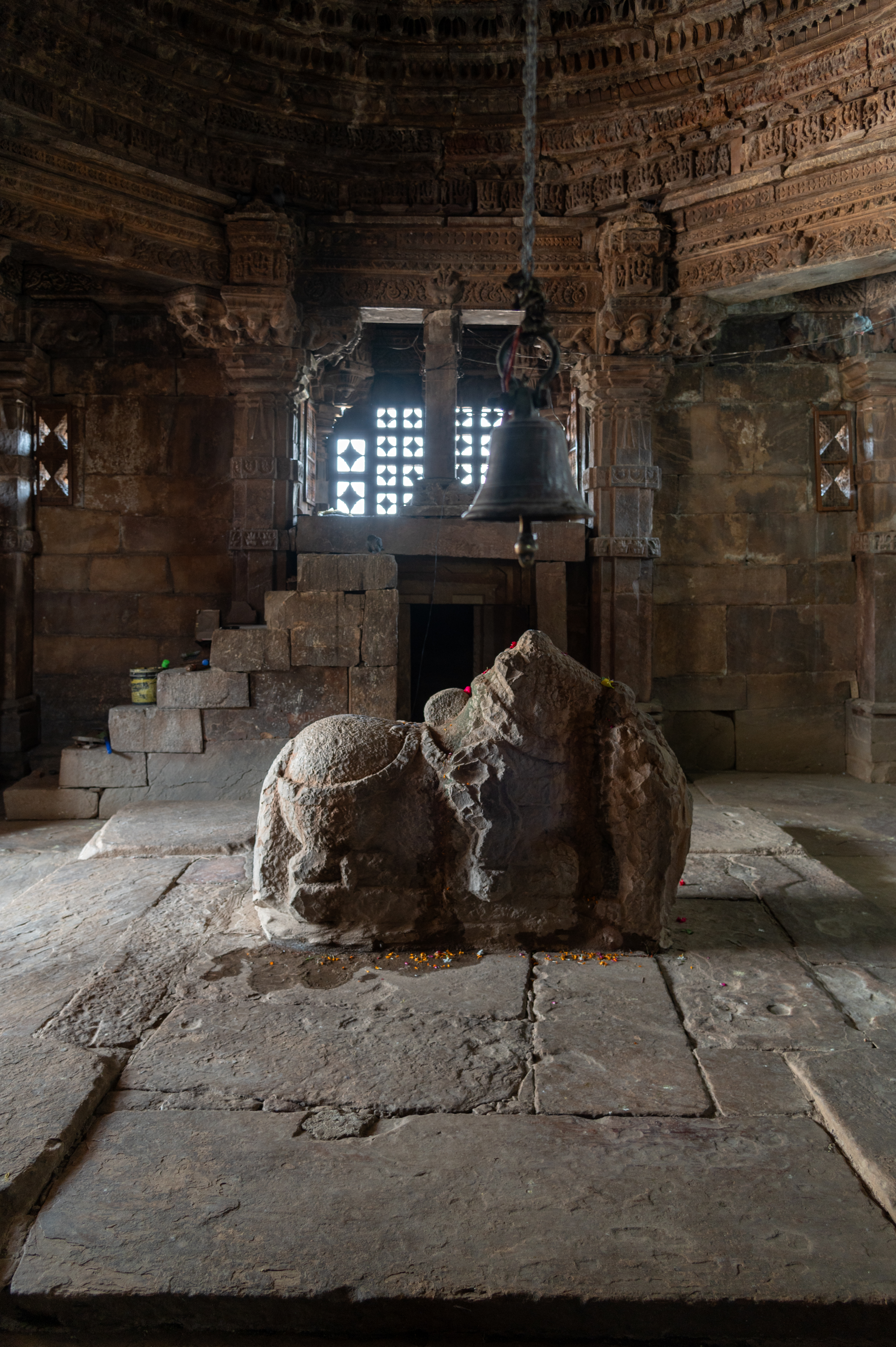 The mandapa (pillared hall) of the Mahakal Temple is a square, enclosed hall with simple stone walls, featuring pairs of pillars at the cardinal points and pilasters at the corners. In the centre lies a platform with a Nandi statue. Adjacent to this, on the right-hand side, there is a small underground water passage. Above this passage, a raised platform can be accessed via a flight of steps. Notably, there is jali (lattice) work adorning this side of the mandapa.