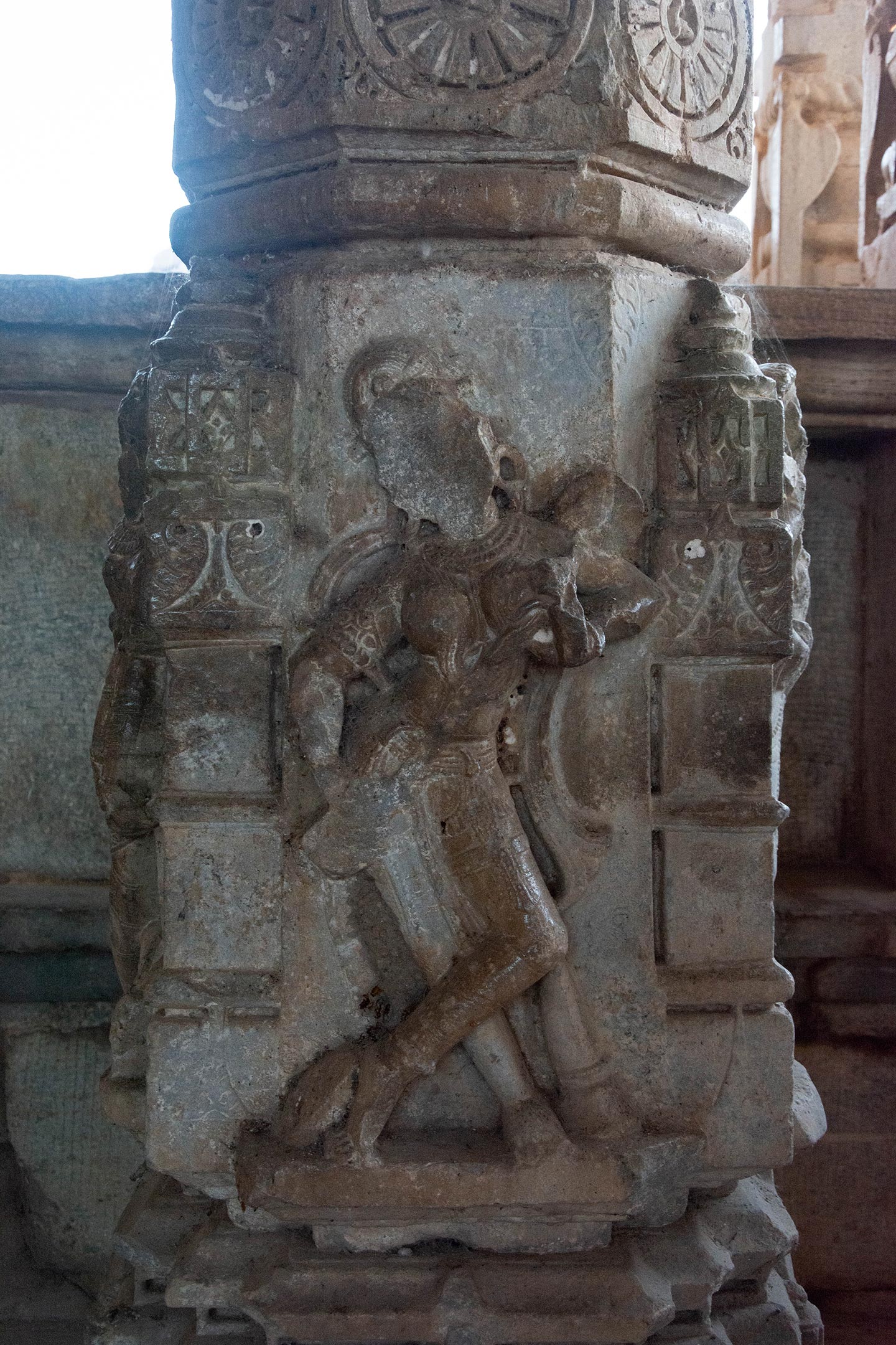 The square portion of the shaft of the pillar in the mahamandapa (pillared hall) is carved with a niche on each of its four faces. Within these niches are figure sculptures depicting various scenes: some portray apsaras (celestial damsels) engaged in activities such as playing musical instruments, dancing, or playing with a ball. Others depict yogis (ascetics) or royal figures engaged in acts of veneration. One niche notably showcases a sculpture of a four-armed Bhairav.