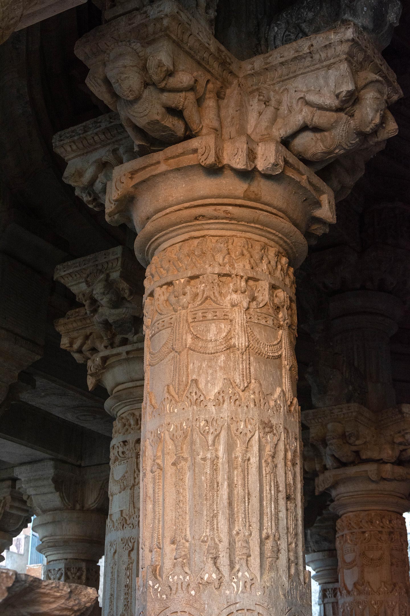 The ceiling of the mahamandapa (pillared hall) is supported by eight elaborately carved tall pillars. Each pillar begins with a square base, transitioning into a shaft that is square in the lower portion, octagonal in the middle portion and circular in the upper portion. Above these sections are architectural mouldings, a shaft that supports the capital and carved bharvahakas (mythical flying load-bearing figures).