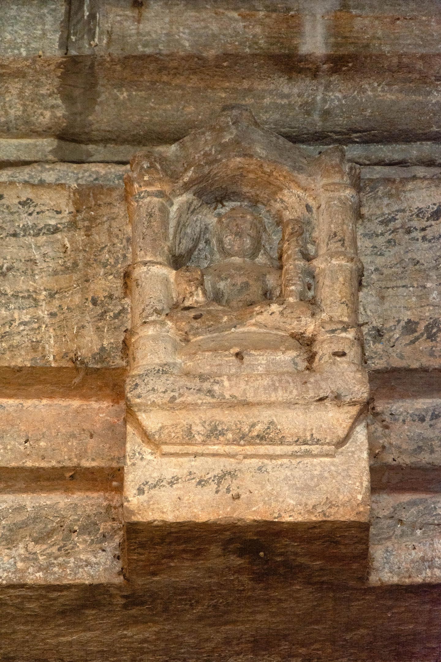 The lintel of the sanctum-doorway features a depiction of Lakulisha in padmasana (lotus pose) with two arms, displaying dhyanmudra (the hand seal gesture for mediation). In his left hand, he holds a lakuta (club), while his right hand grasps a fruit, as per his standard iconography. The image is housed inside a niche on the lalatabimba (lintel). On either side of the lintel, there are depictions of four-armed Brahma on the left and four-armed Vishnu on the right. This substitution of Shiva’s image with Lakulisha at the lintel niches of the sanctum doorway was once a common feature of the Pashupata tradition.