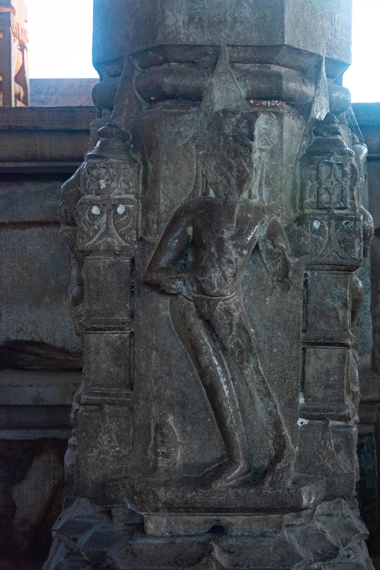 The ascetic is shown on one of the pillars with a long beard and what seems like a jata (matted hair). A kamandalu (water carrier) is slung over one of his shoulders with a rope. He is depicted wearing nothing but a kopina (loincloth) and the janeyu (sacred thread), which is prominently displayed. The presence of the janeyu signifies the Brahmin lineage of ascetics in the Pashupata sect, tracing back to Lakulisha and his four disciples. Lakulisha himself is depicted elsewhere in this temple with a prominent janeyu. The minimalist clothing and kamandalu symbolize his asceticism.