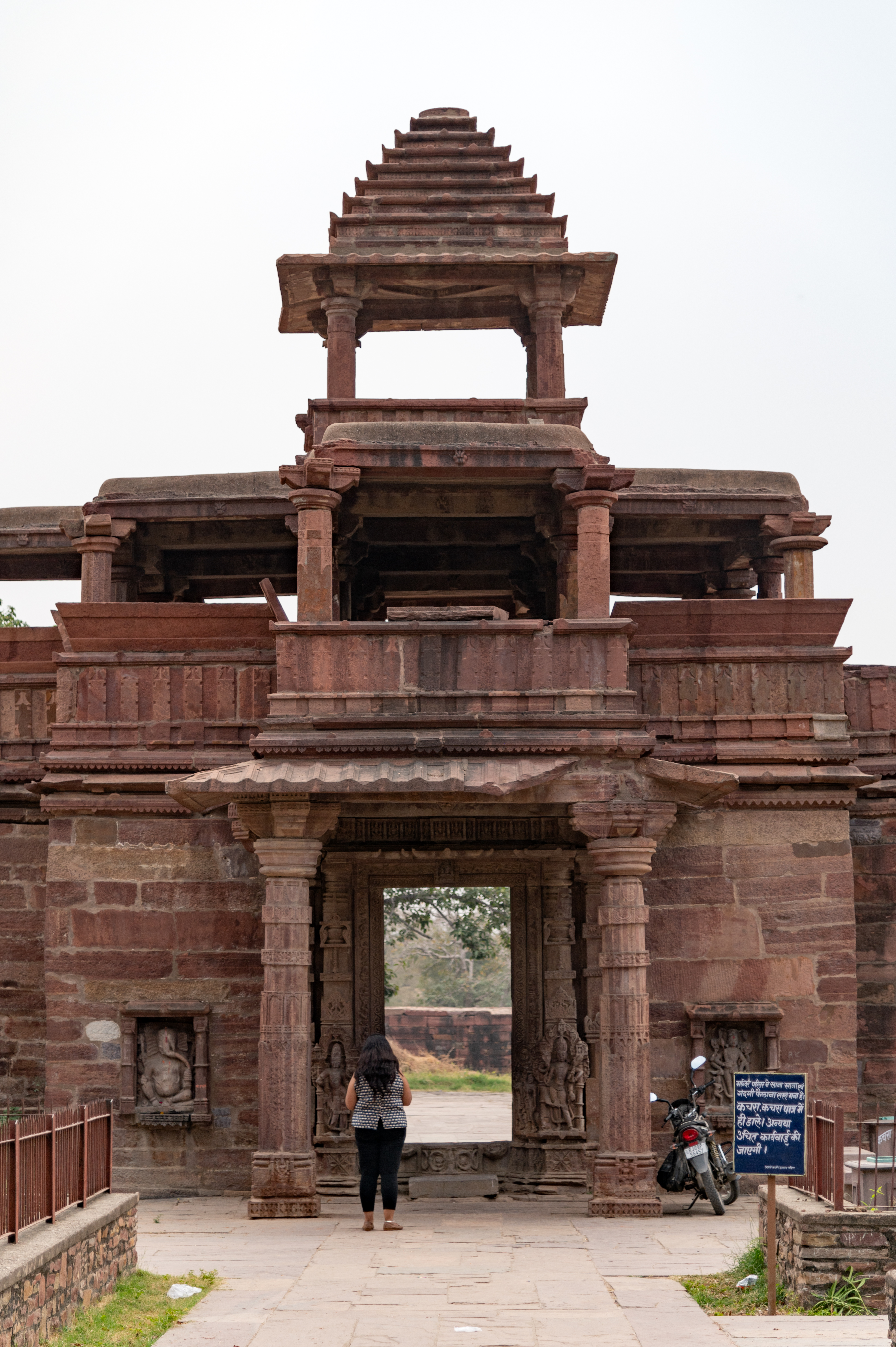 The north-facing view of the two-story entrance gateway to the Mahanaleshwar temple complex is depicted here. It is a semi-open space with a porch on the ground floor, a plain balcony with dwarf walls on the first floor, and a canopy with a pyramidical spire on top.