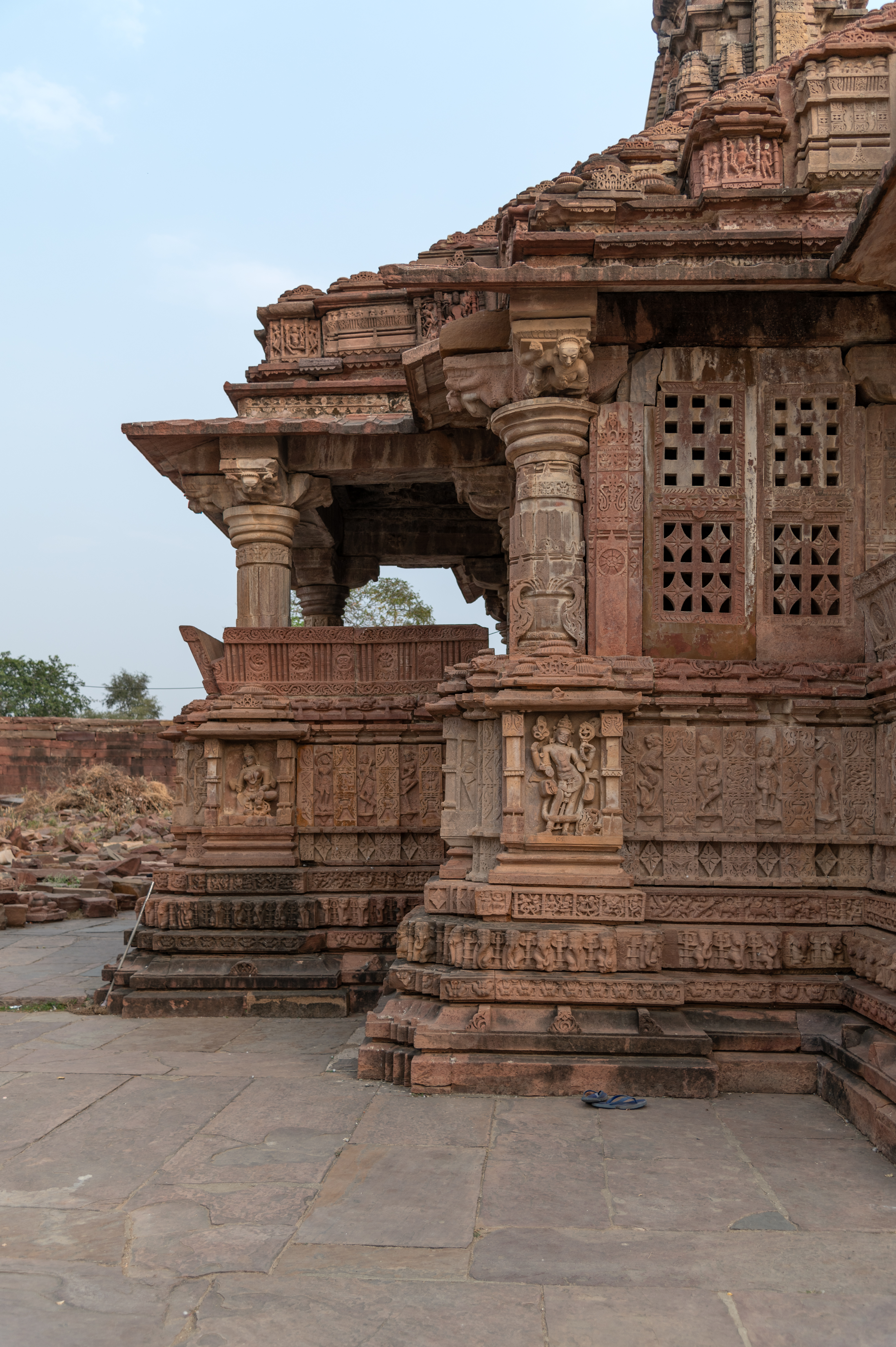 Here are the details of the east-facing mandapa (pillared hall) of the Mahanaleshwar Temple walls. The mandapa's walls, which are connected to the mukhamandapa (front porch), have jalavatayanas (perforated windows). On the north and south sides of the mandapa, there are lateral transepts with dwarf walls. Kakshasana (seatbacks) runs all along the mandapa's transepts. This kakshasana has dwarf pillars on its corners. Just below the pillars are niches containing images of deities. The east-facing mandapa walls have images of dikapala (gods of the cardinal directions) and river goddesses.