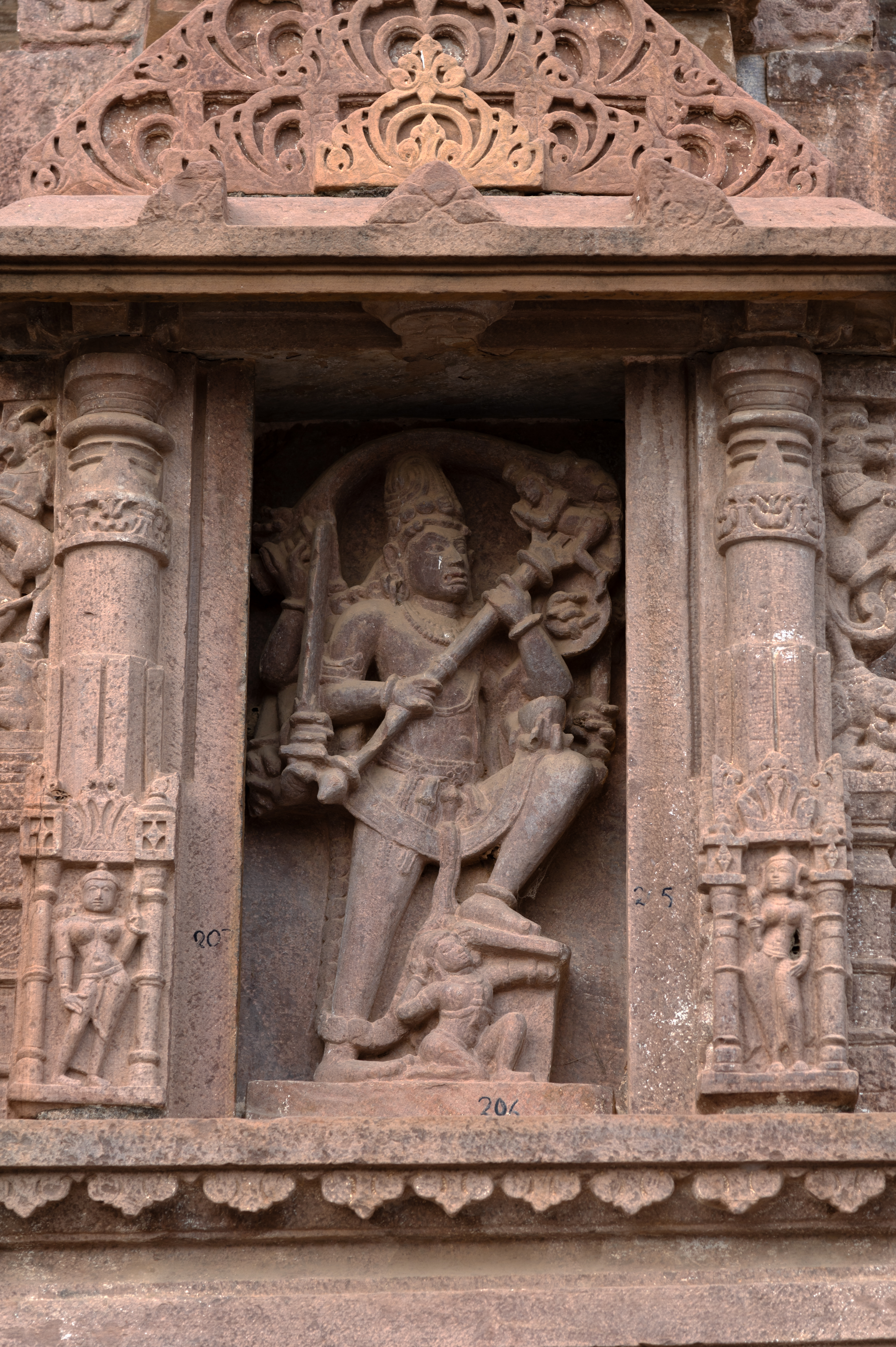 The Mahanlashwar Temple's south-facing bhadra (central projection) features an image of Tripurantaka Shiva. The deity lifts his left foot to crush the demon. The deity holds a raised trishula (trident), kapala (skull), sword, and snake among other attributes. The other two bhadras of the temple compliment this depiction of Tripurantaka with Natesha and Chamunda, indicating the temple's affiliation with Shaivism.