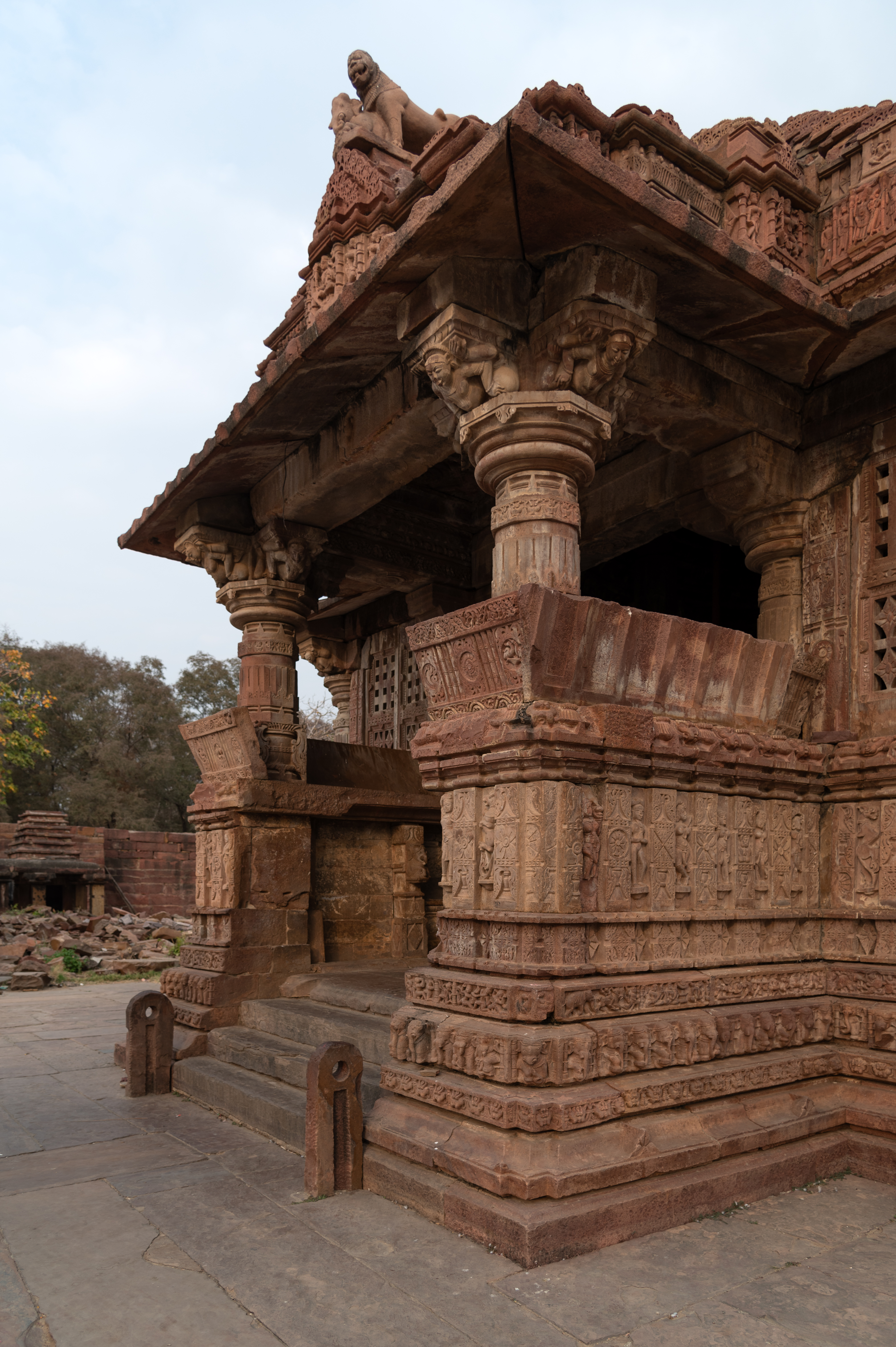 The main entrance (facing west) to the Mahanaleshwar Temple is seen here. The mukhamandapa (front porch) has a square design and is semi-open. The two front pillars support the cantilevered projection. Dwarf walls, adorned with kakshasanas (seat backs), surround the pillars on both sides.