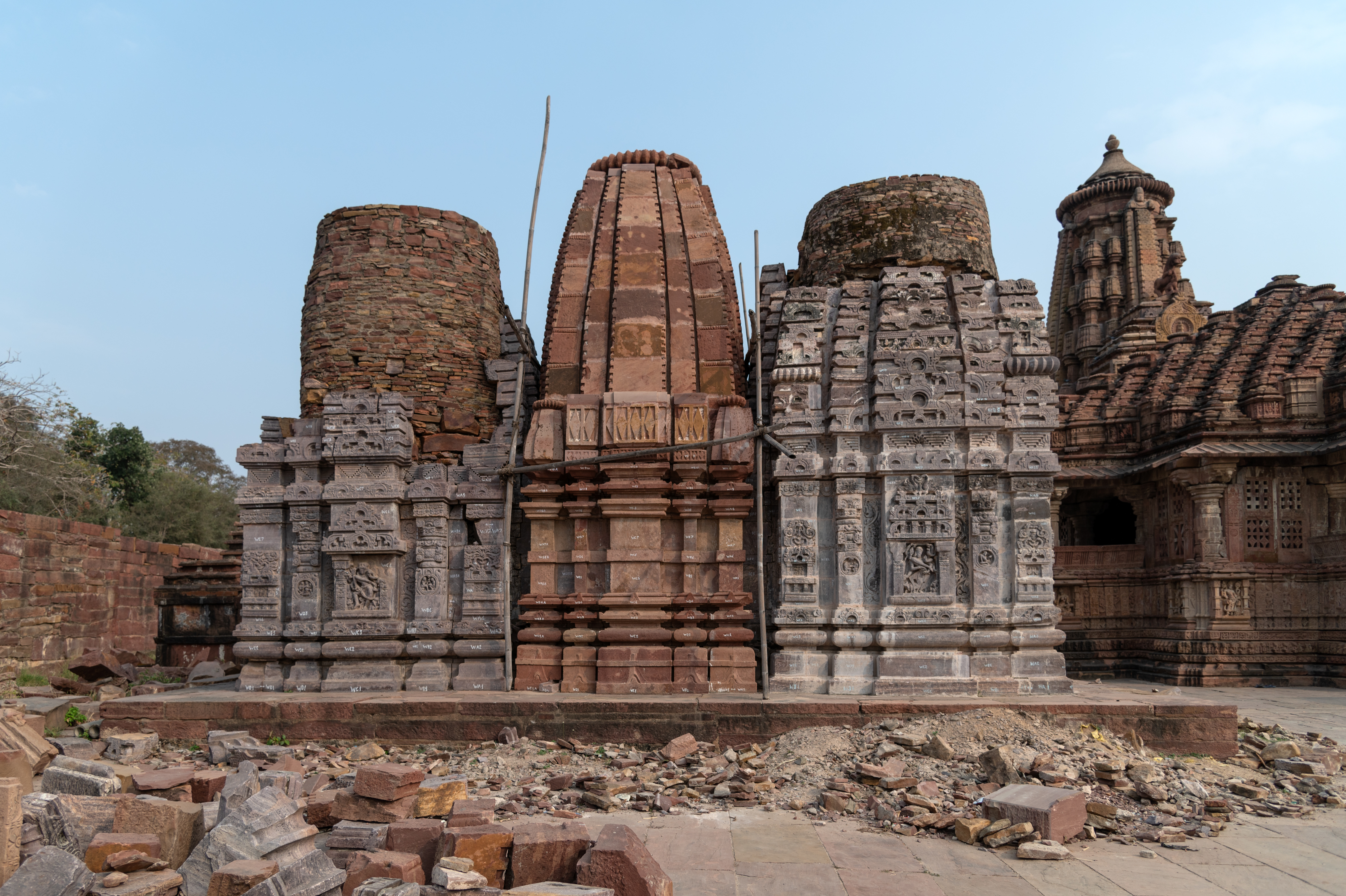 A triple-shrine temple cluster, facing east, stands near the Mahanaleshwar Temple. According to Michael W. Meister, this cluster is one of the earliest temples in the Mahanaleshwar temple complex. Based on style, the north and south shrines from this triple shrine belong to the 8th century CE. Meister argues that the central shrine in the triple shrine was a later period addition. The construction material for the older two shrines is completely different from that of the central shrine. The red sandstone of the central shrine is similar to other monuments in the Mahanaleshwar temple complex. The Archaeological Survey of India (ASI) has reassembled the older shrines as part of its restoration work.