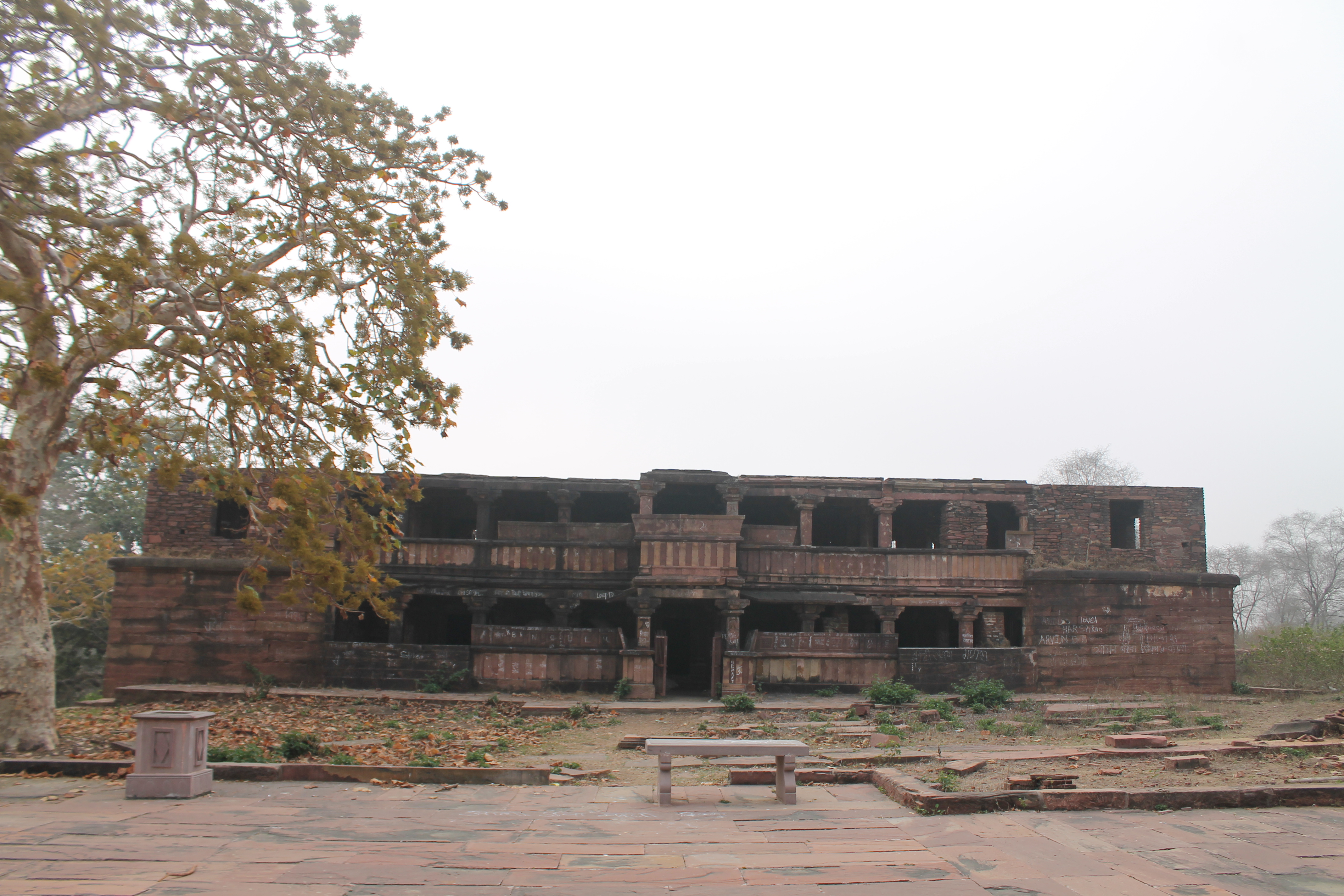 The north-facing façade of the residential building, a Shaiva matha from the Suhaveshwar temple complex, can be seen here. It is a two-story structure with several rooms on both floors. The matha is in ruinous condition. There are several breaks in the exterior stone of the matha.