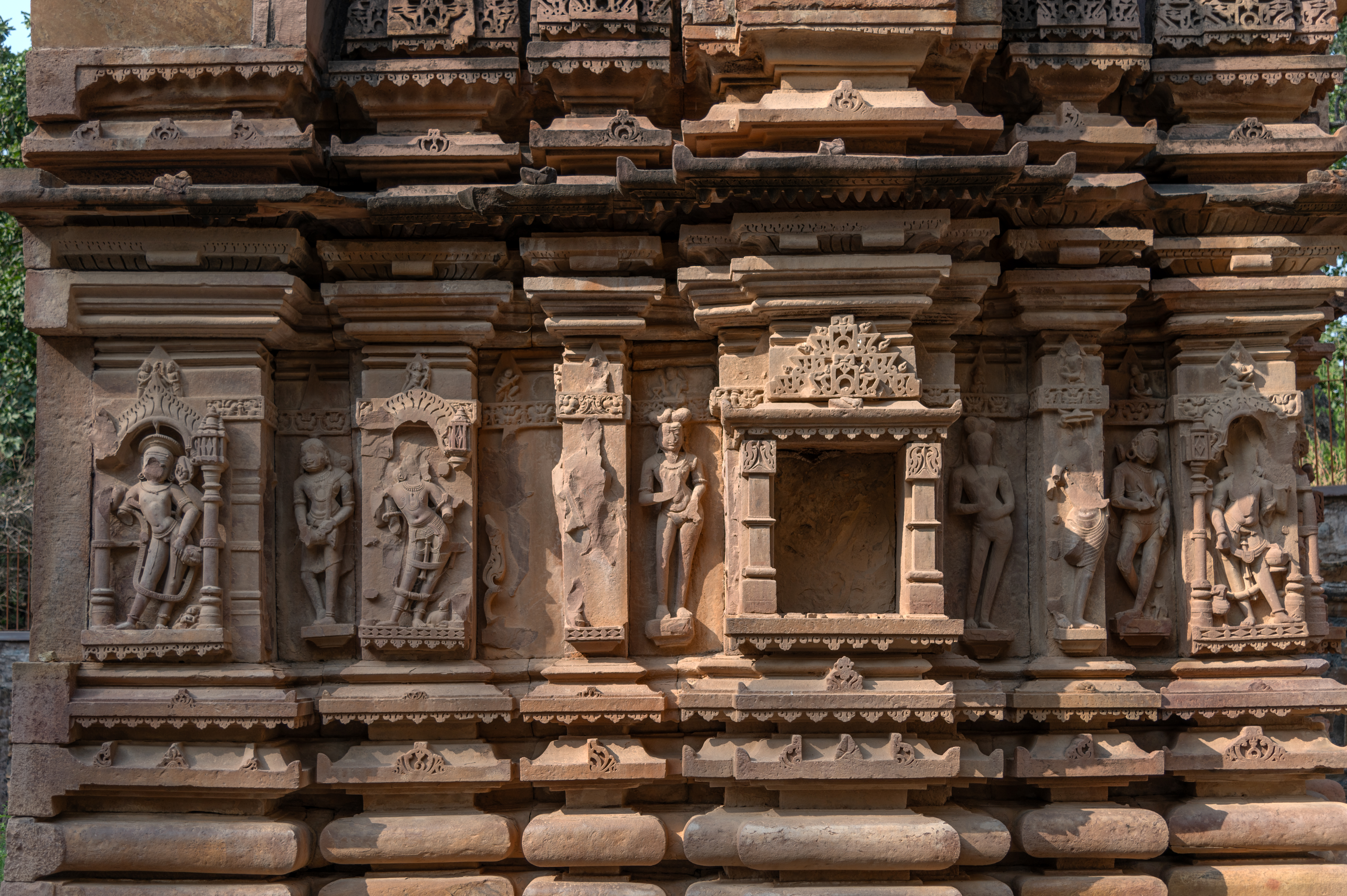 The jangha (wall) of the Kaner-ki-Putli Temple has central offsets flanked by projections and recesses. The niches of the central offsets on all three sides of the garbhagriha (sanctum sanctorum) are presently empty. These niches may have originally been adorned with depictions of deities. The remaining projected and recessed sections are intricately carved with depictions of minor deities, including dikapalas (deities of cardinal directions), Shaiva ascetics and female figures.