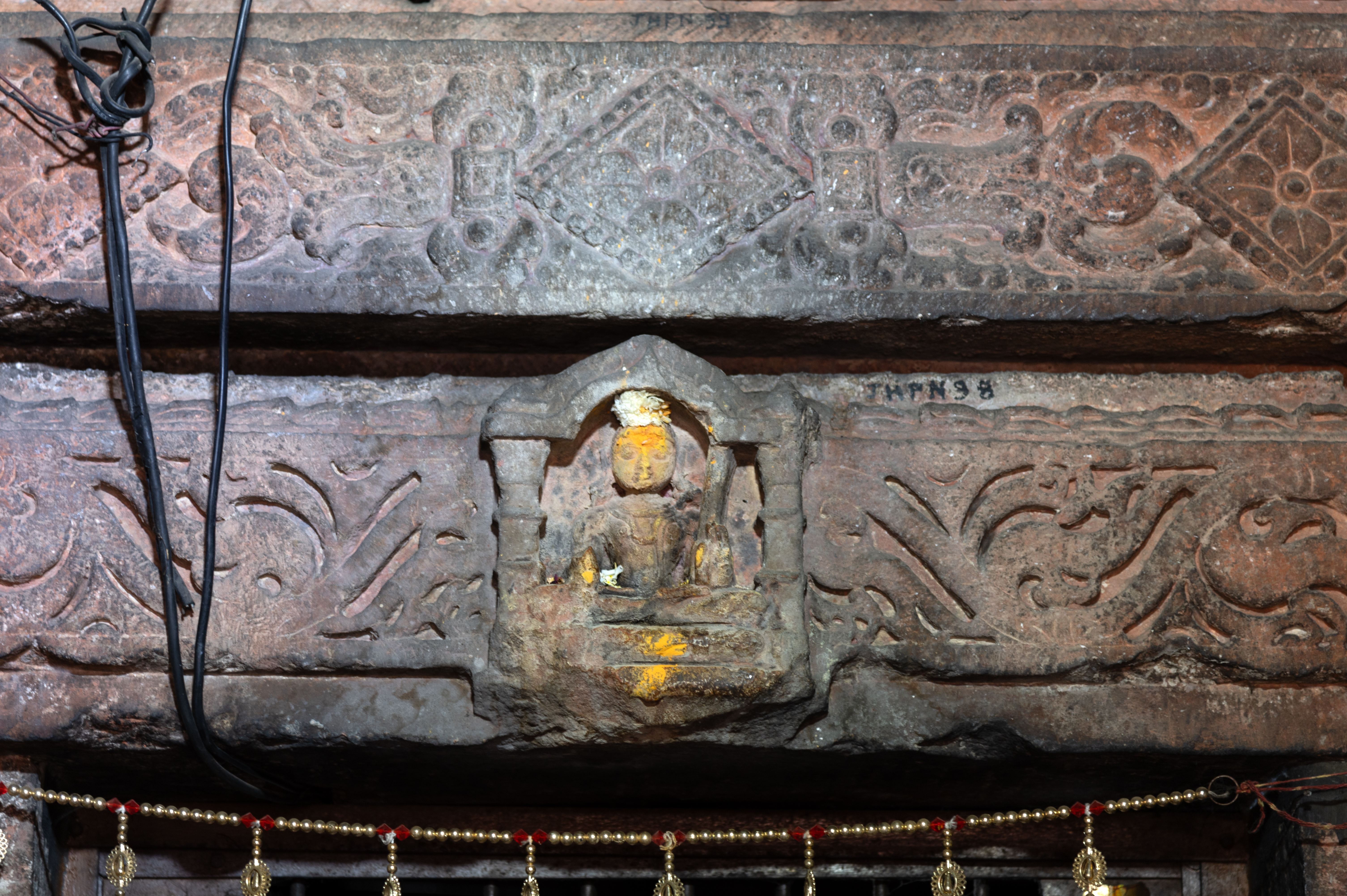 Inside a niche on the lalatabimba (lintel) is a depiction of Lakulisa, a preceptor of the doctrine of the Pashupata tradition of Shaivism. He is seated in padmasana (lotus pedestal pose), holds a danda (staff), phala (fruit), and wears a yajnopavita (sacred thread).