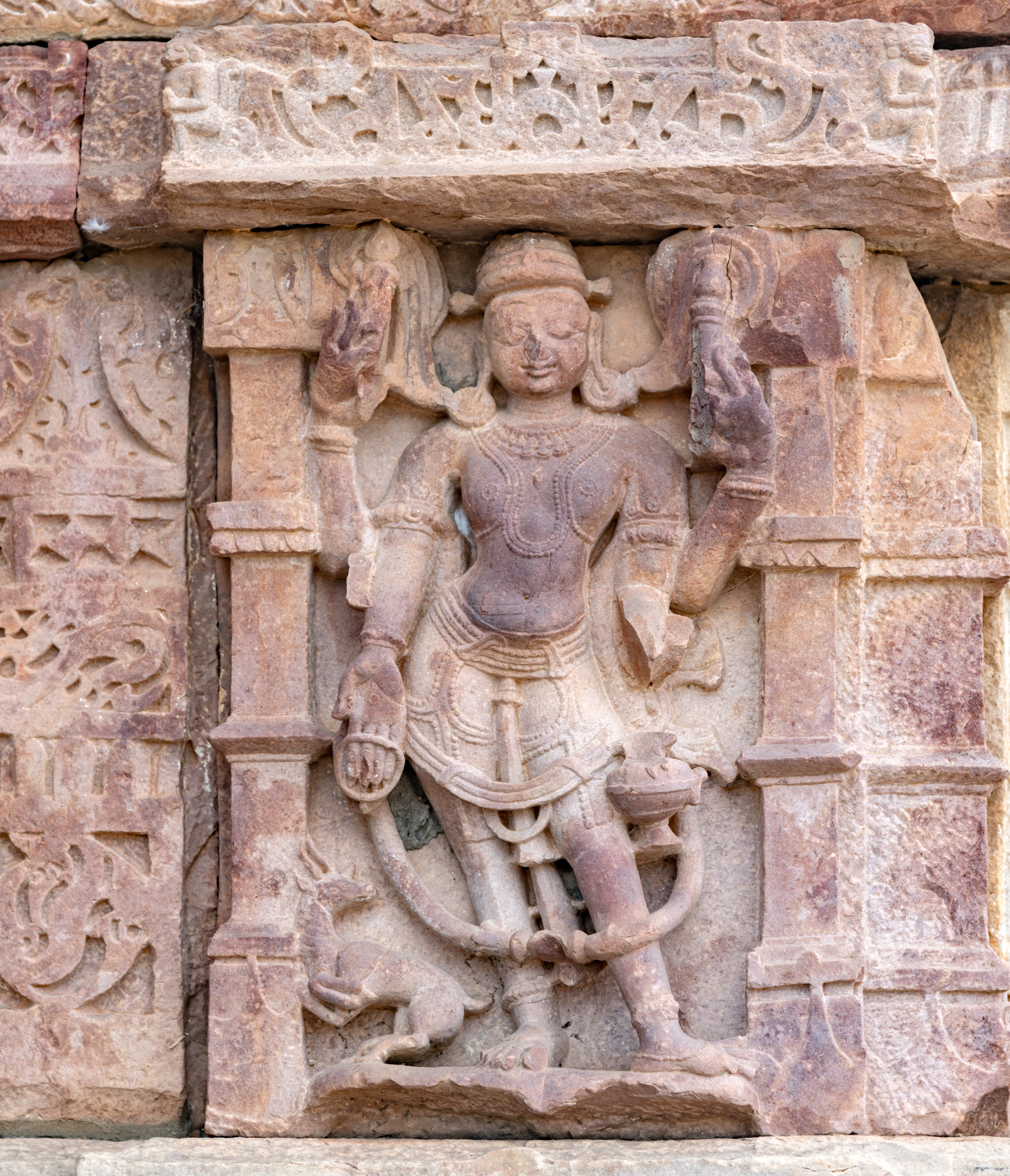 Vayu is depicted standing with a gentle smile. His four arms bear testament to his celestial nature. In his upper hands, he grasps a staff, symbolizing authority and guidance. His lower hands cradle a kamandalu (water pot) and extend in varadaksha (boon-giving gesture with a rosary). At the base, his vahana (mount), the antelope, is depicted in graceful motion, adding to the dynamic energy of the scene.