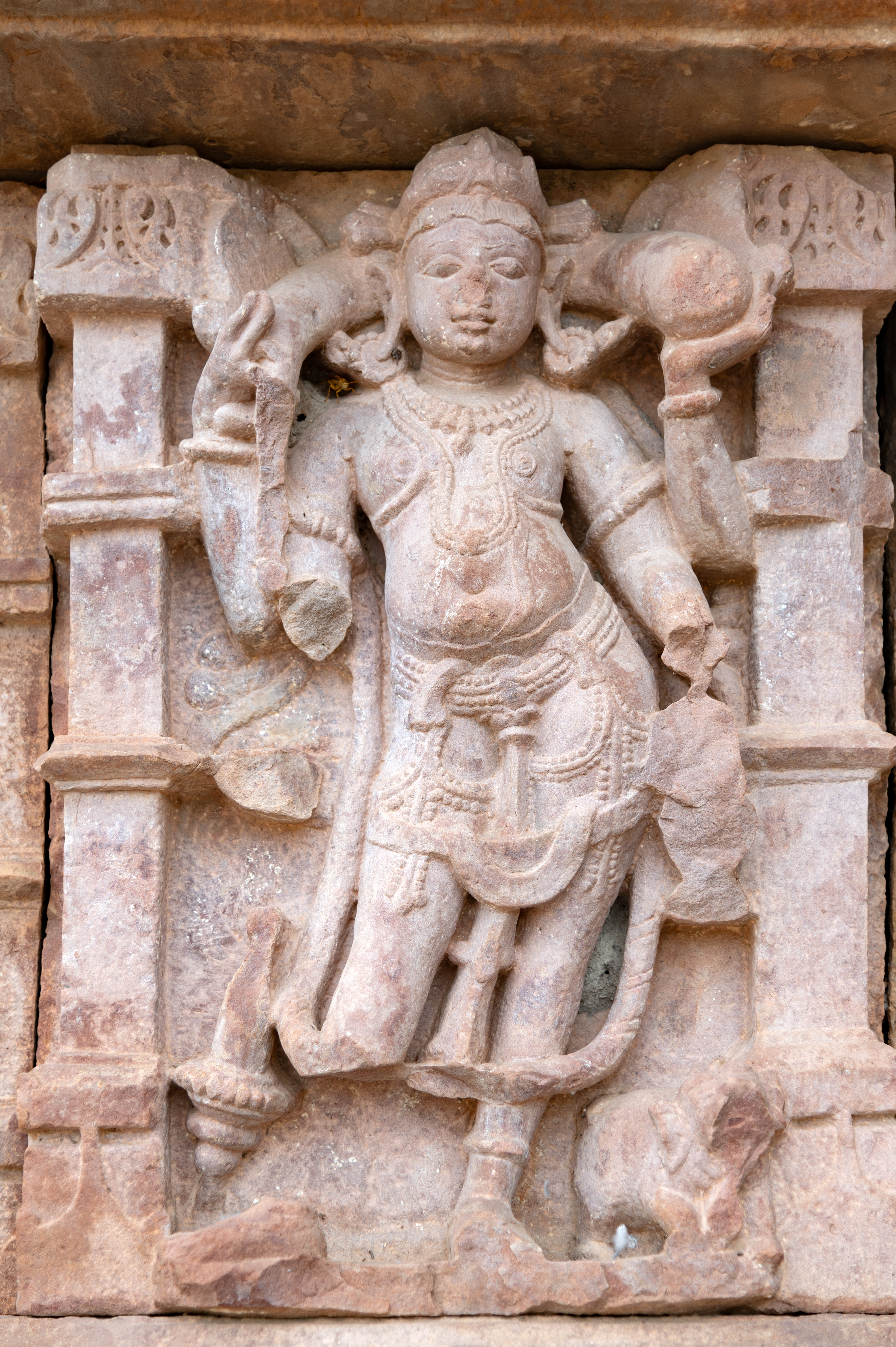 Kubera, accompanied by his mount, the elephant, is depicted with four arms. In his upper arms, he holds a symbol of wealth and abundance —a money bag. Though his lower arms are damaged, it is evident that he once wielded a gada (mace) in his lower right hand and a kamandalu (water pot) in his lower left hand.