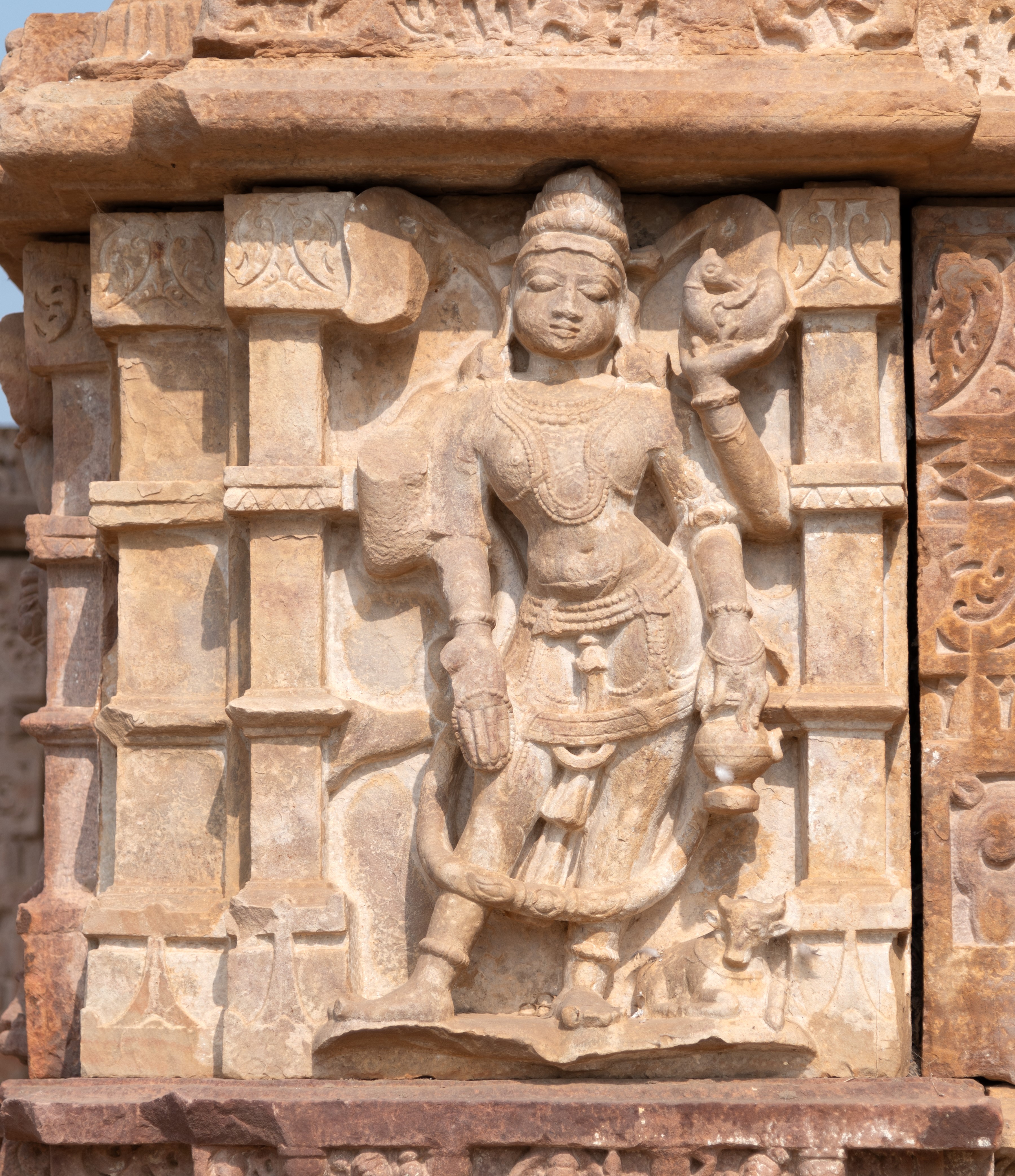 Yama, the God of justice and guardian of the south direction, is depicted holding a rooster and a kamandalu (water pot). One of his hands is in varada hasta (boon-giving gesture). He is adorned with jewels and wears a long garland. At the bottom left is a carving of a buffalo.