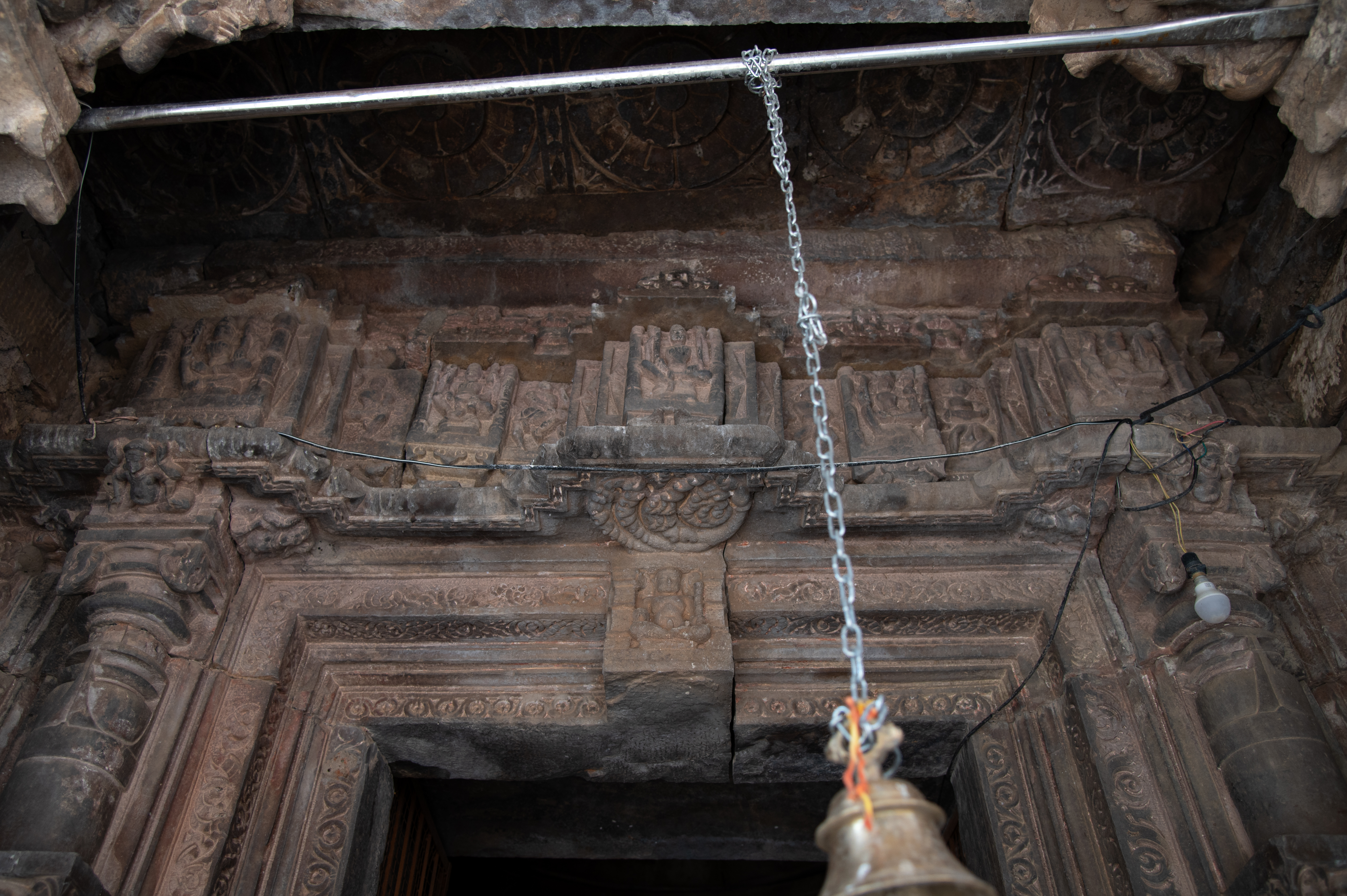 Image 12:  The lalatabimba (central portion on the door lintel) of the garbhagriha (sanctum sanctorum) doorframe features a seated figure of Lakulisa, while the panel above depicts four-armed male deities, each seated and holding their respective attributes.