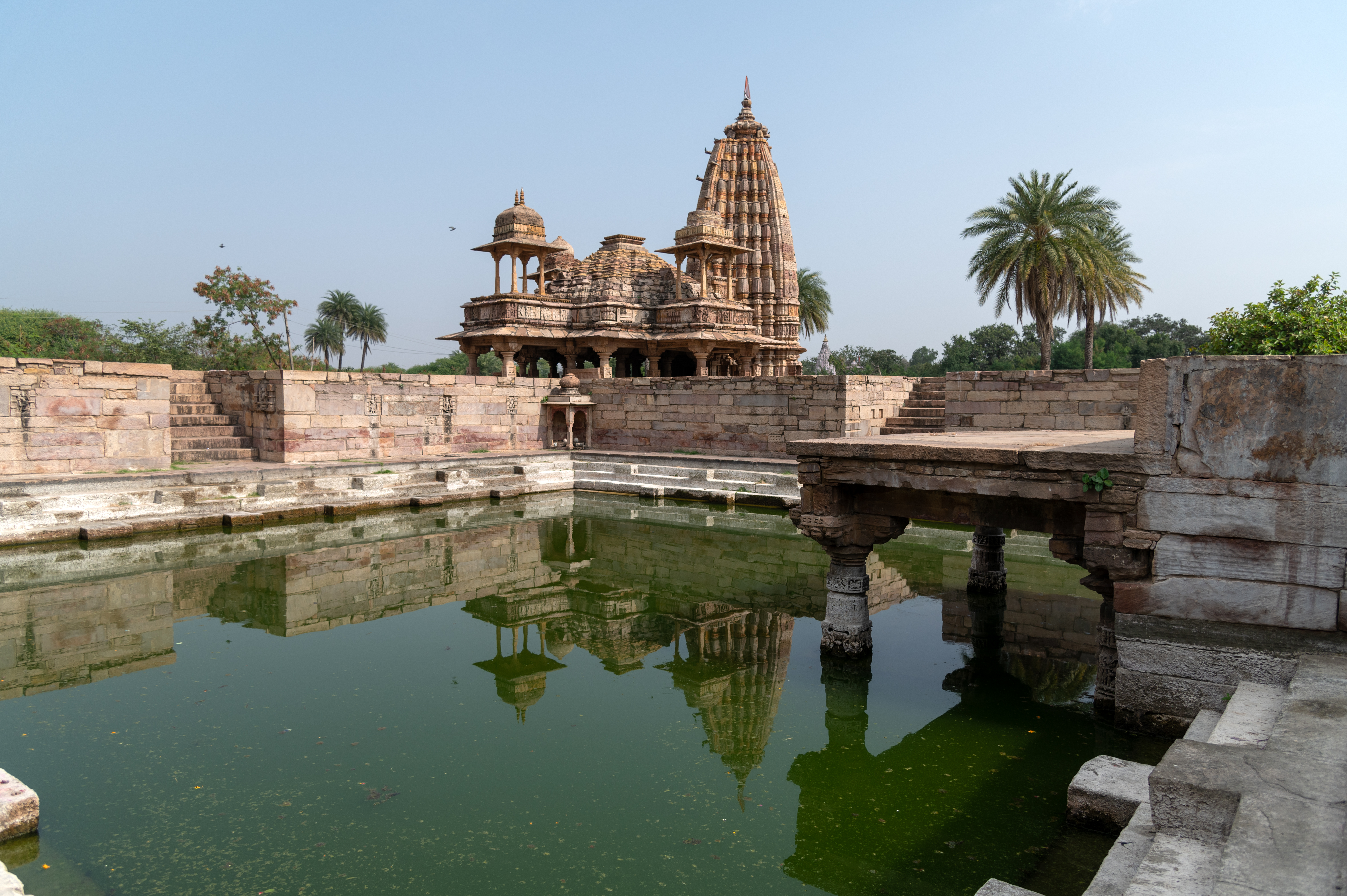 Image 1:  The Mandakini Kund, within its enclosed wall, reflects the towering shikhara (superstructure) of Undeshwar Temple on its tranquil waters.