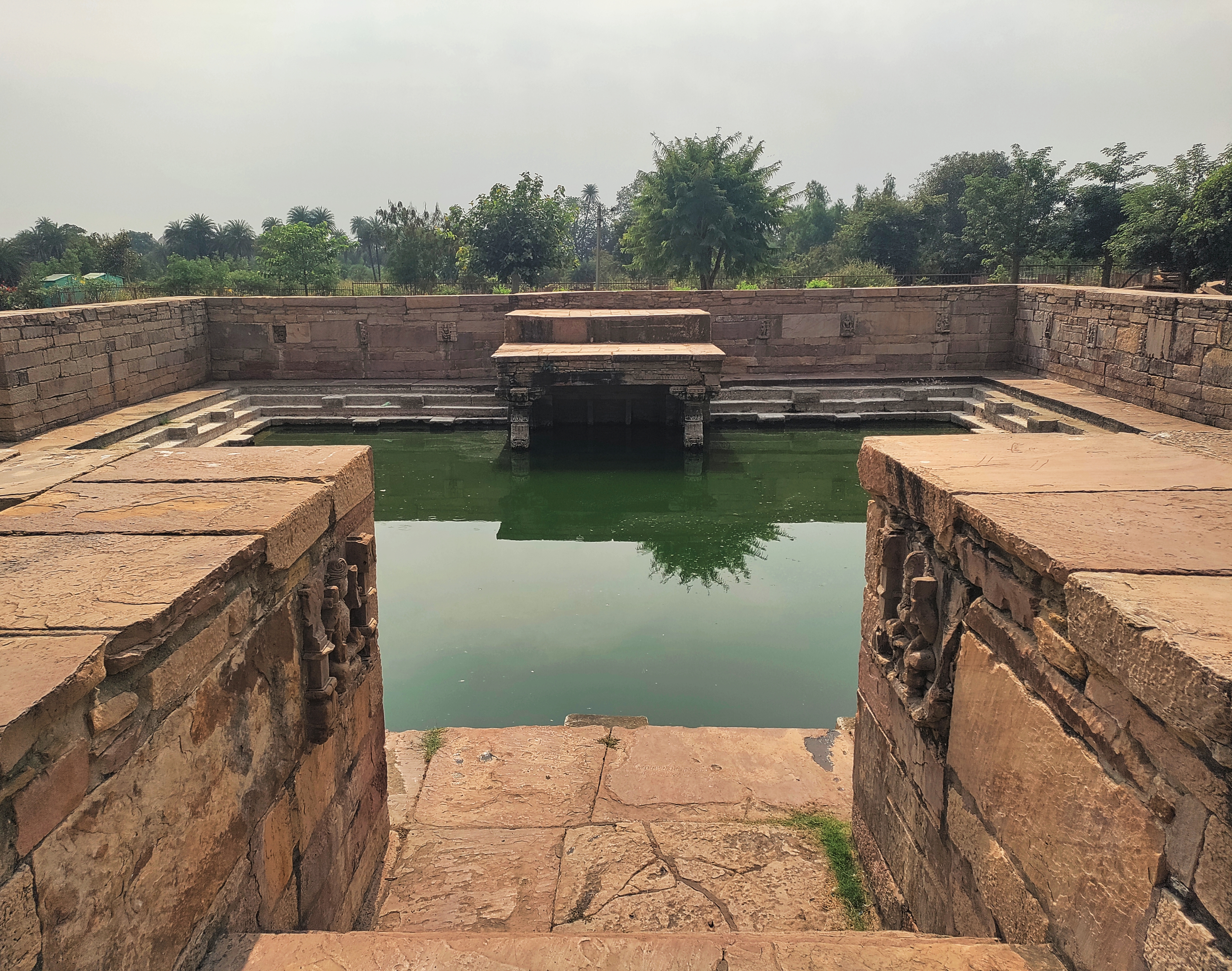 Image 4: The Kund is square-shaped with entrances on three sides and a flat-roofed pillared pavilion on the fourth side.