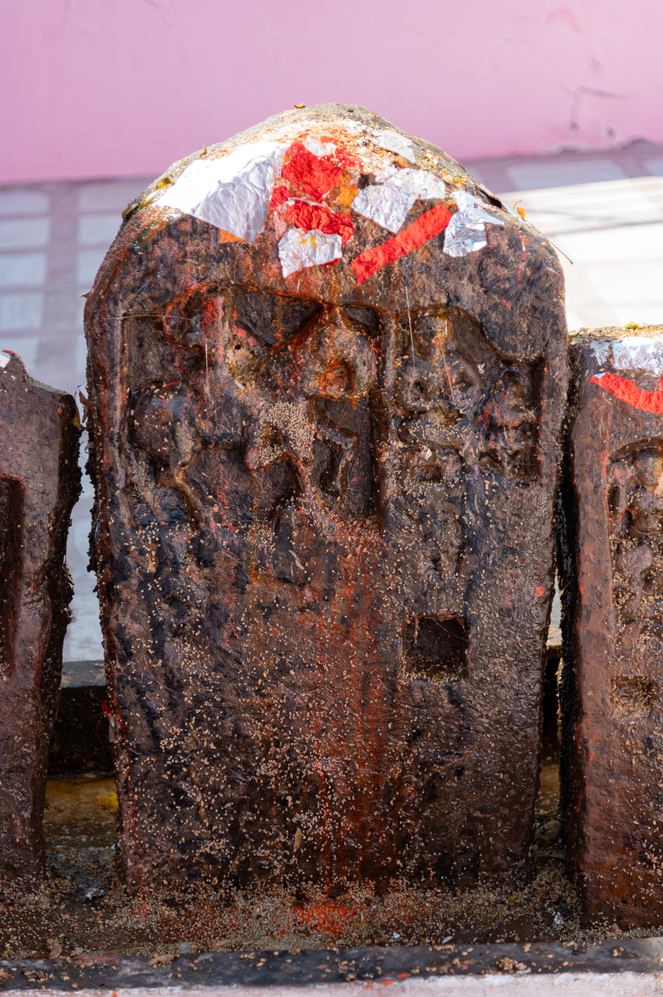  A hero stone fragment measures about a foot in height and half a foot in width, featuring a slightly different depiction than the other hero stones. In this fragment, the hero is portrayed mounted on a horse, accompanied not by a celestial damsel but by another human figure kneeling down. This second figure could also be a depiction of the hero. The scene symbolizes the hero’s journey to heaven after his death, where he bows down to God, often represented by the depiction of Shiva in his linga (aniconic representation of Shiva) form. The undulating stone surface of the hero stones makes it difficult to understand whether it originally contained any inscriptions.
