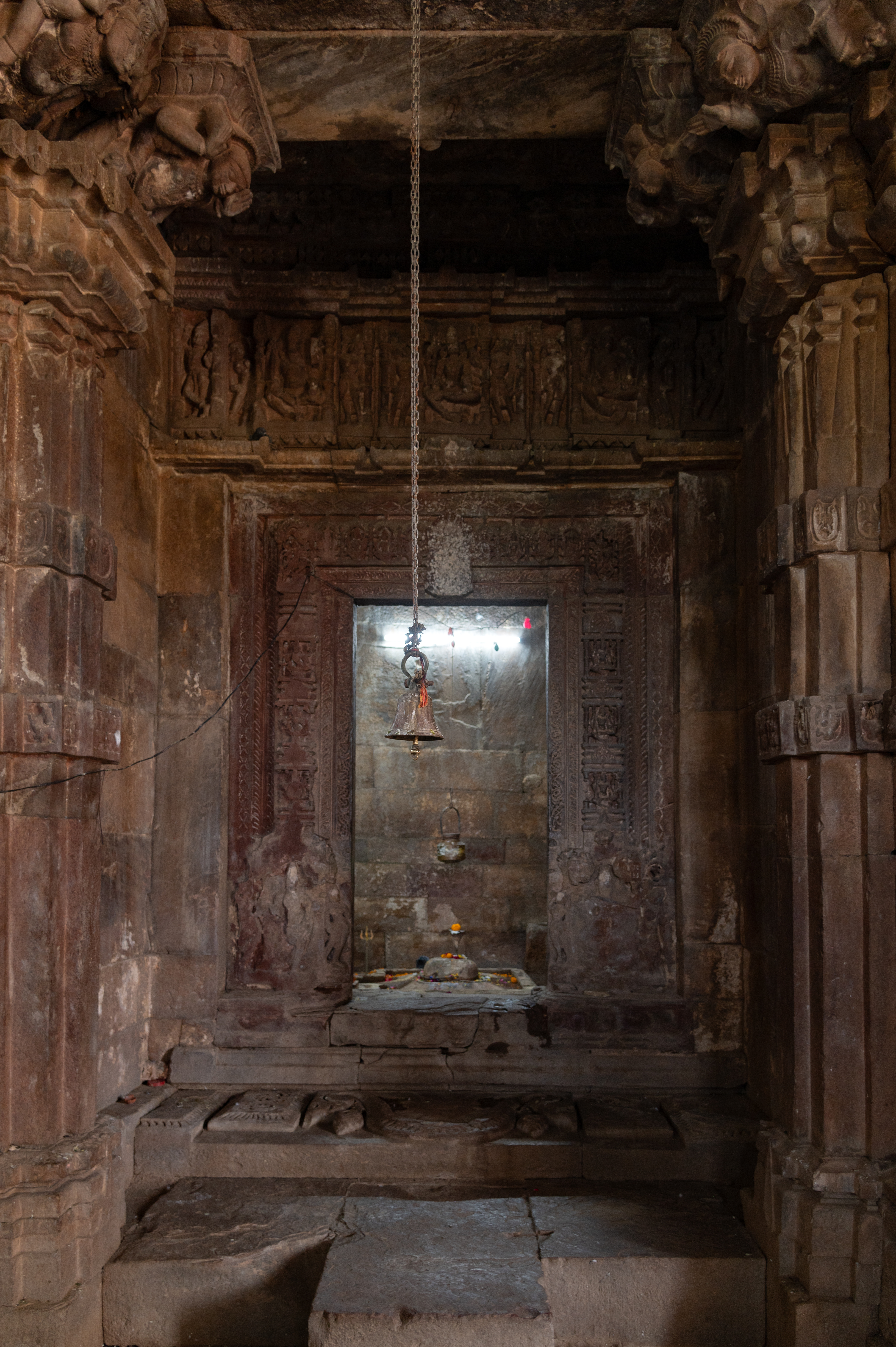 Image 8:  To the south of the mandapa (pillared hall) lies a shrine with an intricately carved, multi-shakha (vertical bands or architraves) doorframe. The doorframe contains niches adorned with Shiva and his manifestations, Matrikas and Ganesh. The lalatabimba (lintel) is covered in white paint, obscuring its details. In the garbhagriha (sanctum), a Shiva linga is placed.