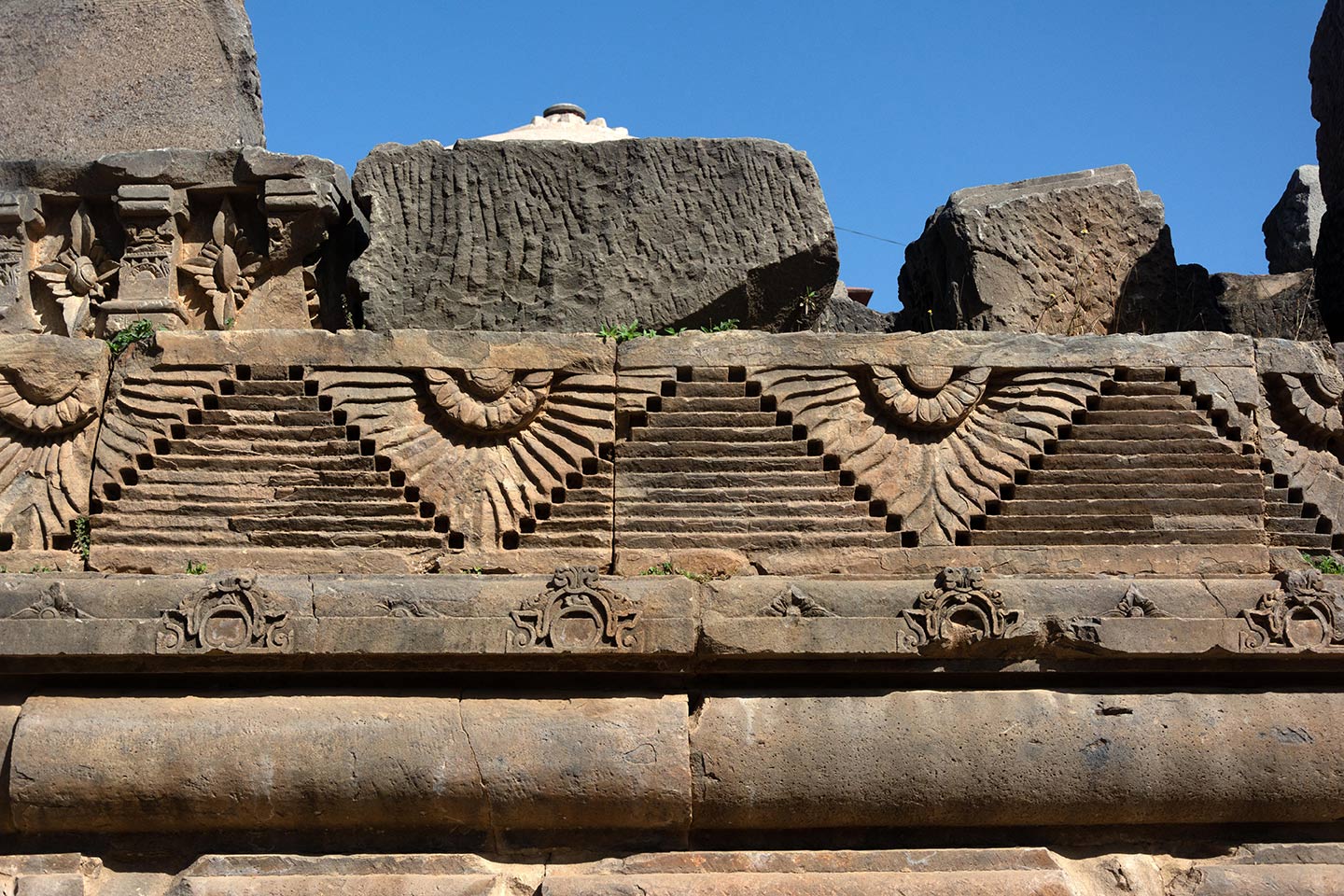 Broken debris from the original temple assembled on the south face of the adhisthana. Relief carvings of geometric, flora and fauna motifs feature all around the adhisthana.