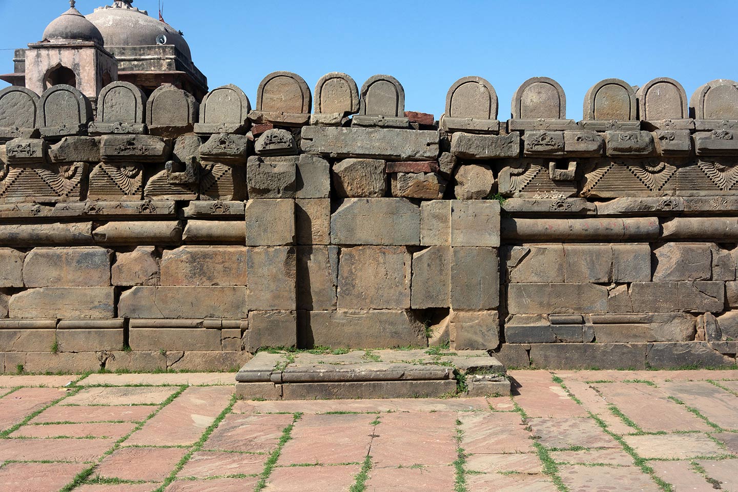 U-shaped rounded stones are assembled on the parapet, but their position or purpose in the original temple is unknown. The projected space attached to the adhisthana (centre) appears contemporary to the original temple and was likely used as a small shrine for the Panchayatan plan. The Archaeological Survey of India (ASI) has paved the pradakshina with stone to the east of the adhisthana.