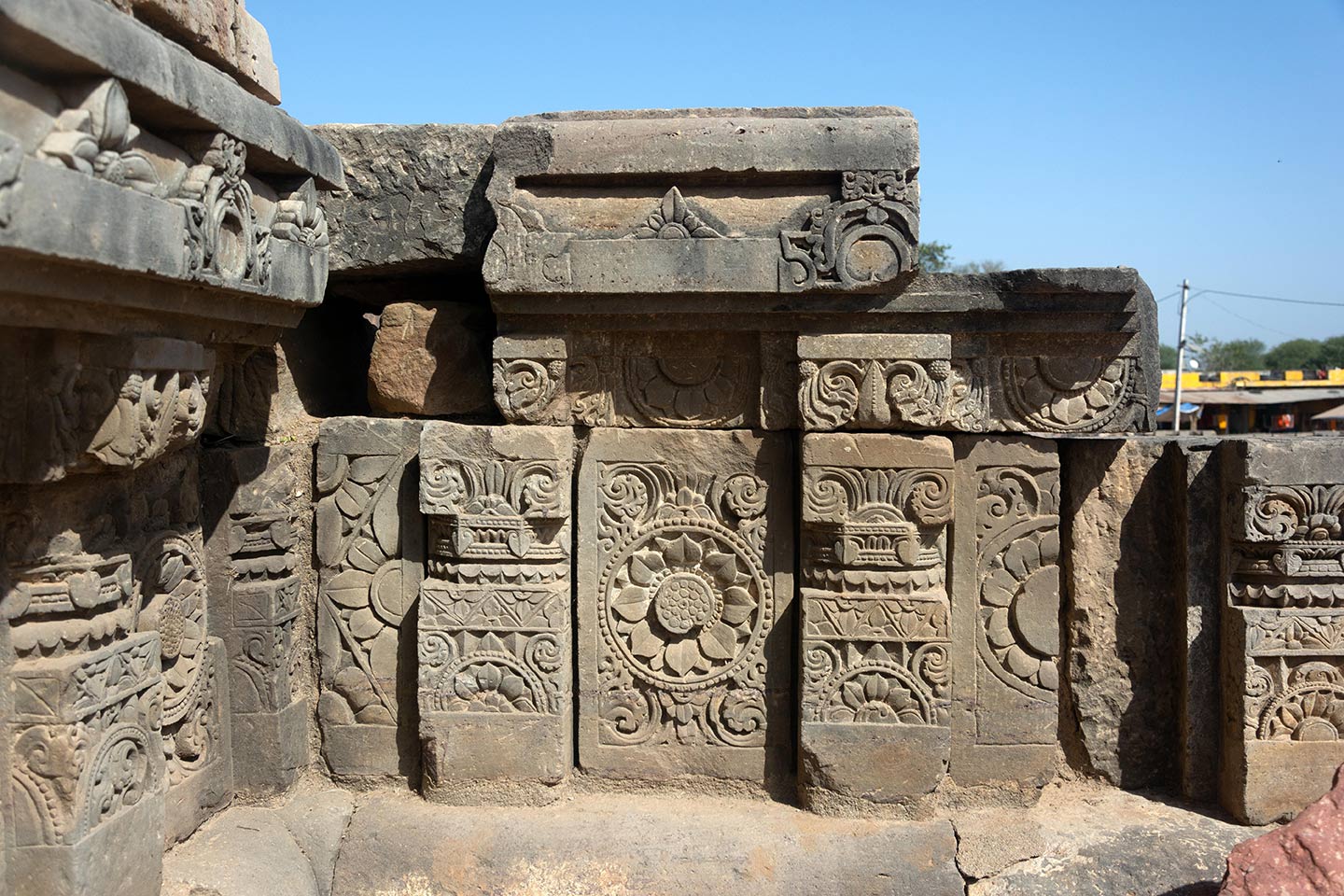 Tablet-like plaques are placed on the adhisthana (facing east). These plaques depict various types of flora and fauna as well as hybrid creatures like kinnara, vyala, and makara. The plaques are tightly arranged, richly detailed, and deeply carved, creating contrasting shadows that make the artwork look three-dimensional in sunlight.