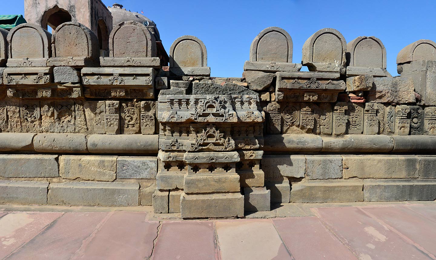 Broken debris from the original temple assembled on the southeast face of the adhisthana. Unknown is the position or purpose of the U-shaped rounded stones on the parapet in the original temple.